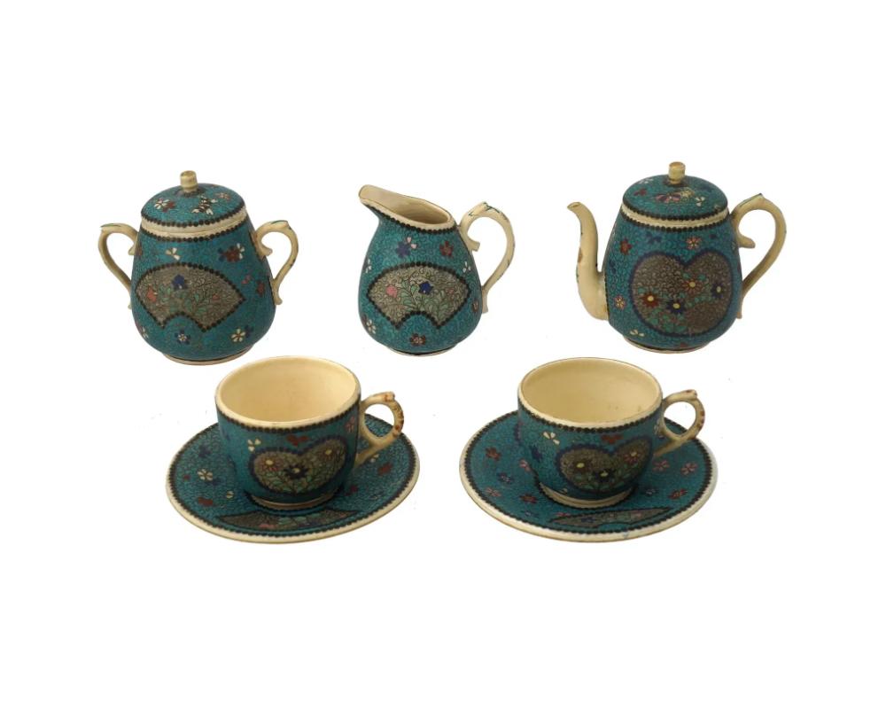 Un juego de té japonés de esmalte sobre cerámica. Un total de 7 elementos. El juego consta de un par de tazas y platillos, una tetera, un azucarero y una cremera. Cada vajilla está adornada con medallones figurados de esmalte policromado que