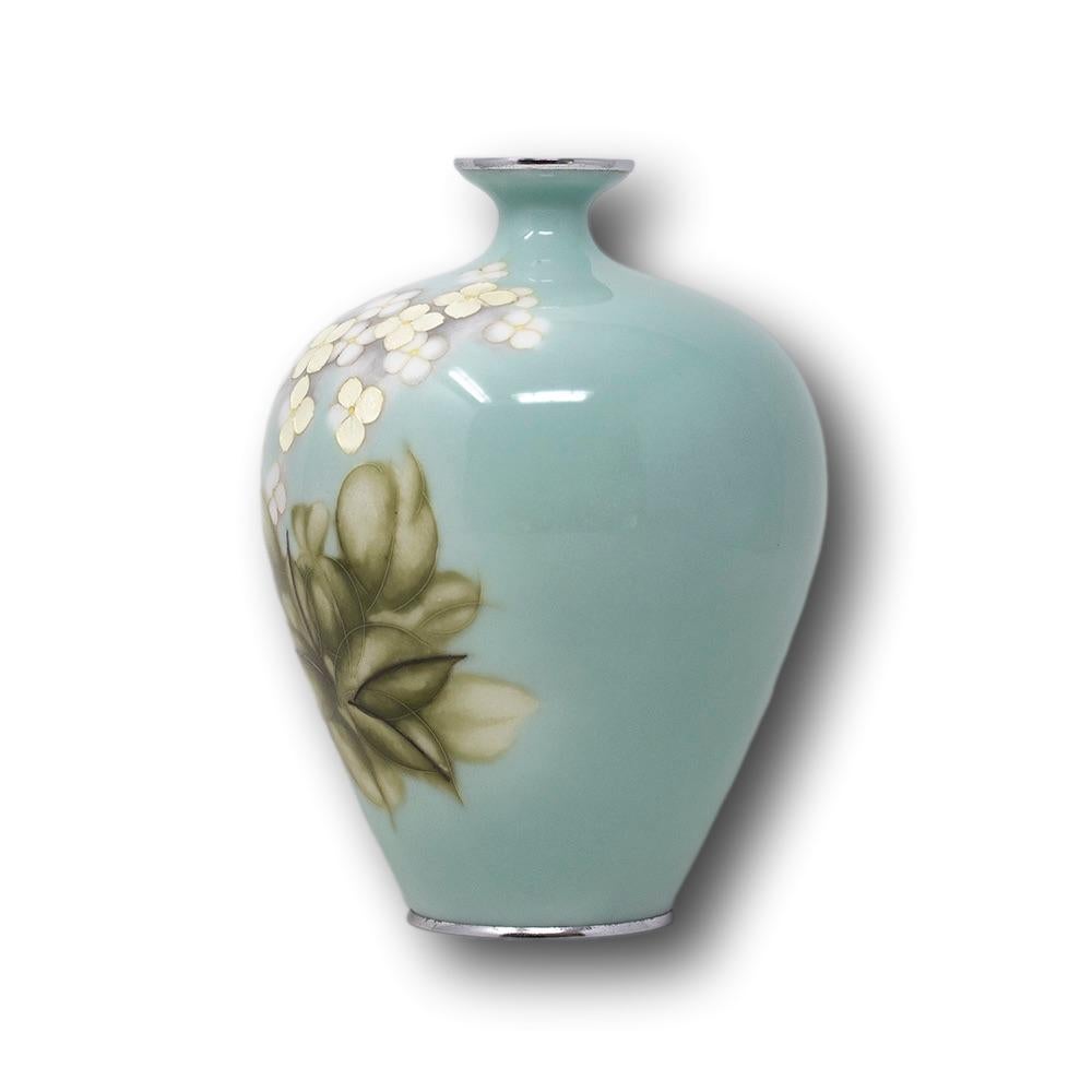 Japanese cloisonne enamel ginbari flower vase Tashio-early Showa period. The vase light blue in colour with gold ginbari petals, amongst partially wireless white petals above green foliage. The base signed Tamura within a silver tablet to the centre