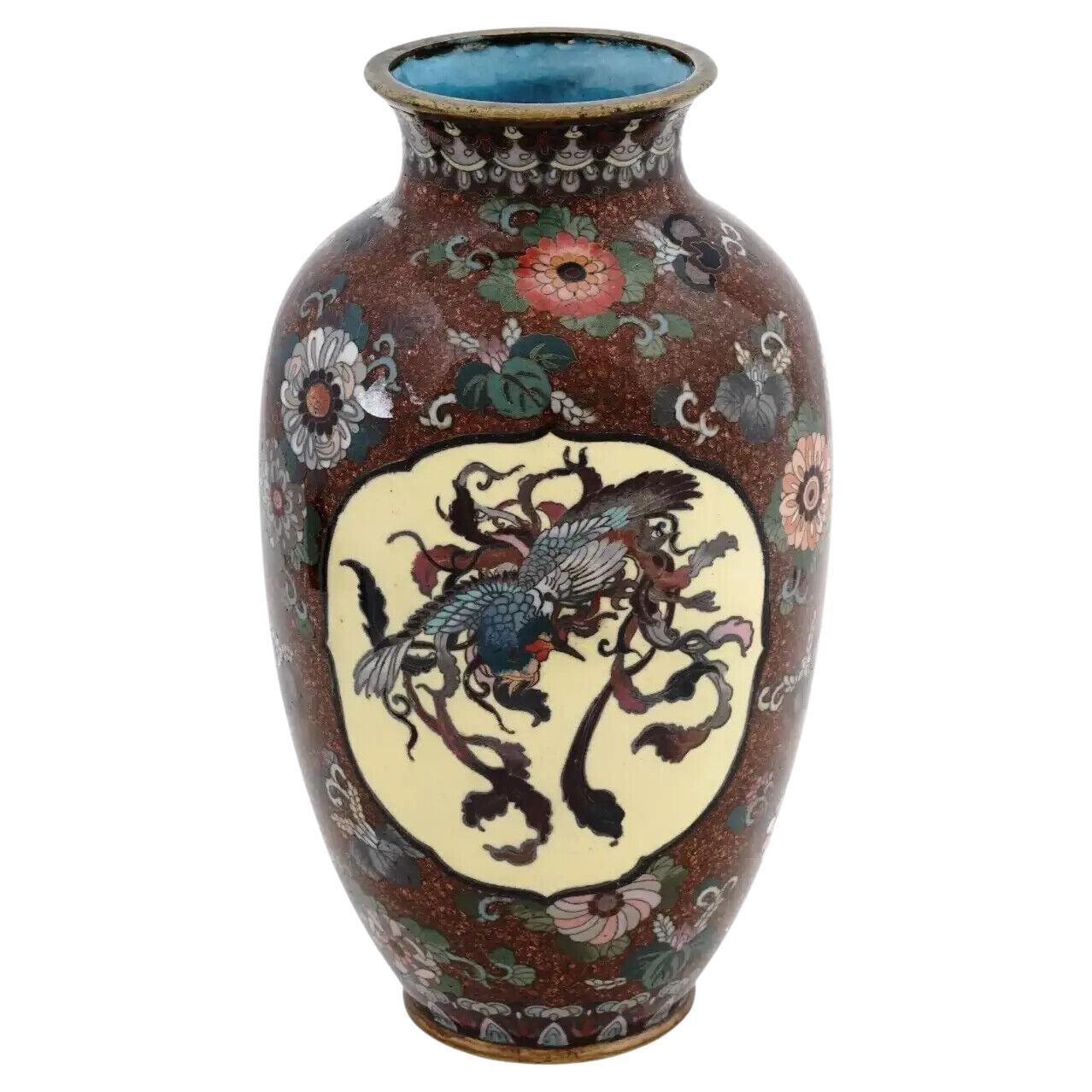 A large antique Japanese Meiji era enamel over brass vase. The amphora shaped vase is enameled with polychrome medallions with a Phoenix bird and a dragon surrounded by floral, and foliage motifs made in the Cloisonne technique. The neck and the