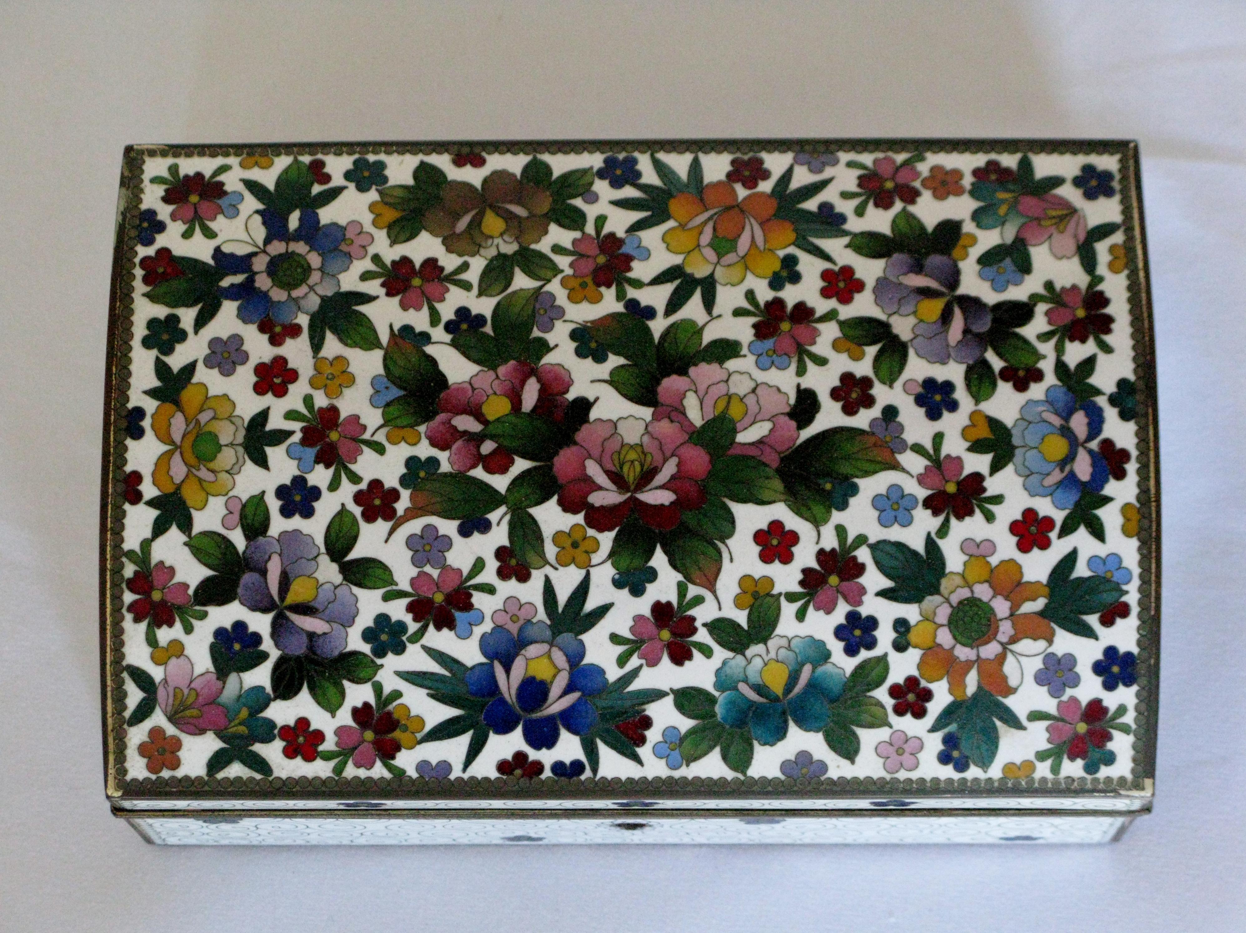 Très rare boîte à bijoux japonaise en cloisonné, vers les années 1960.
 Dessus riche en motifs floraux sur fond d'émail blanc. Intérieur en velours grenat, avec plateau. 
Trou de serrure en laiton, clé non présente.
Ce coffret a été créé pour et