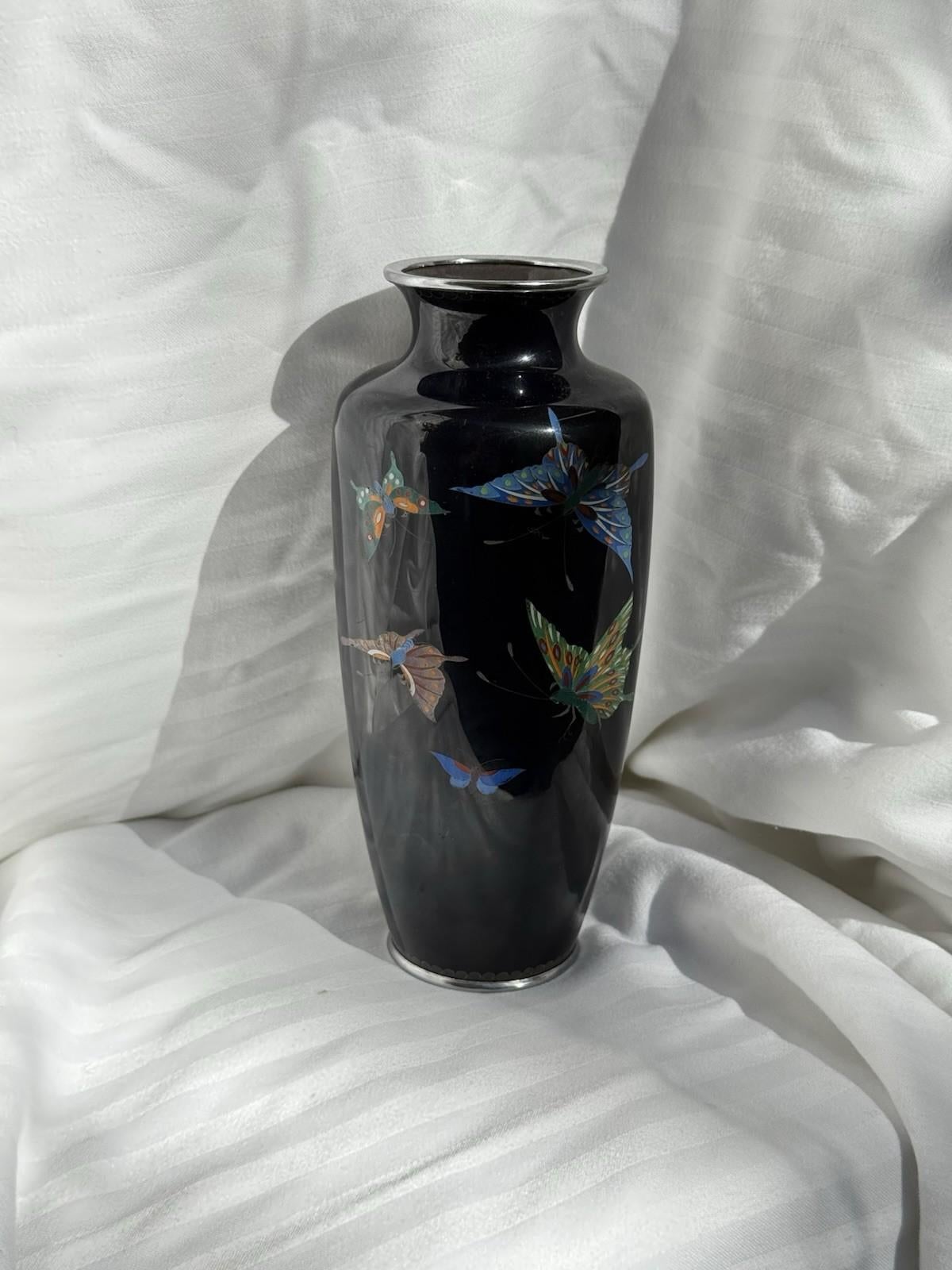Un superbo vaso giapponese in smalto cloisonné attribuito alla bottega di Ando, risalente agli anni '20-'30. Il vaso presenta un sorprendente fondo nero profondo, splendidamente contrastato da farfalle smaltate in tonalità turchesi, arancioni, verdi