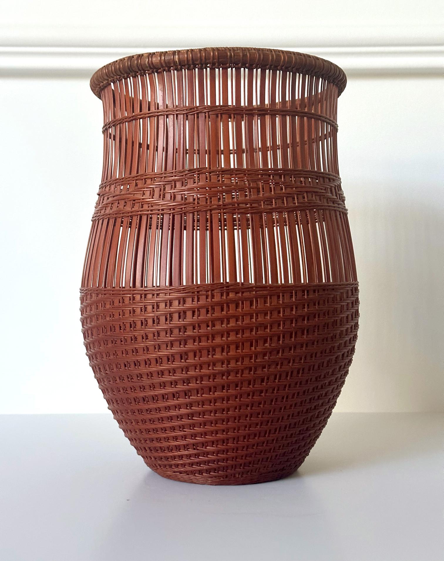 A Japanese Ikebana basket woven by bamboo artist Abe Motoshi (Japanese, b. 1942). In an organic vase form with elegant, curved wall with reinforced rim. The shape calls to mind the Fishermen's trap. The basket was constructed with Madake bamboo and