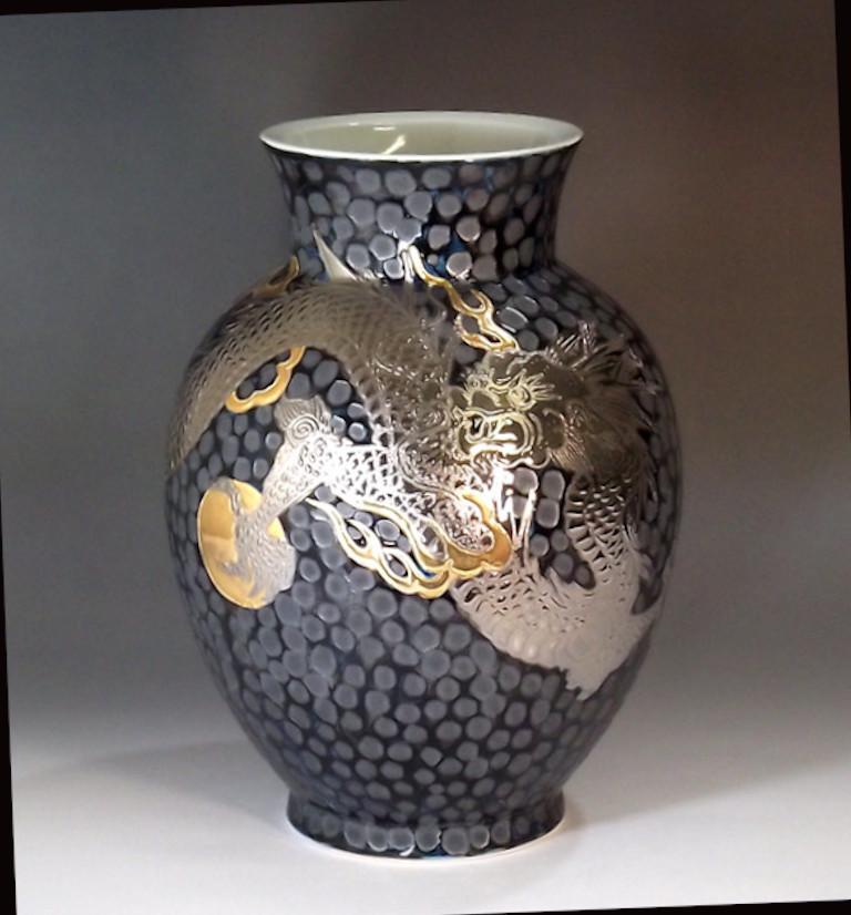 Exquisite contemporary Japanese porcelain vase, hand painted showcasing a dramatic scene of two dragons facing each other set against a dimpled black background, a signed piece from the signature dragon collection by highly acclaimed award-winning