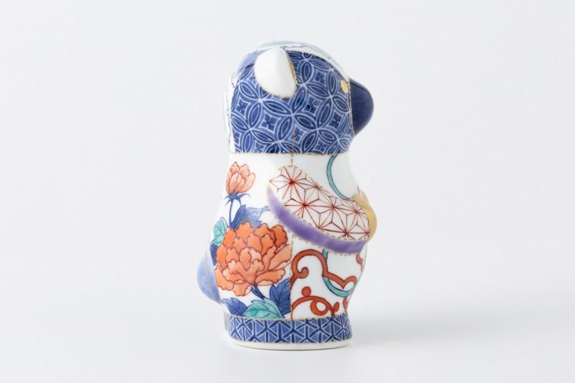 Exquisite Japanese contemporary porcelain bear sculpture, intricately hand-painted in blue, yellow and green in an aupicious traditional Nabeshima technique. The patchwork composition of the pattern creates a charming bear sculpture.
It is a work