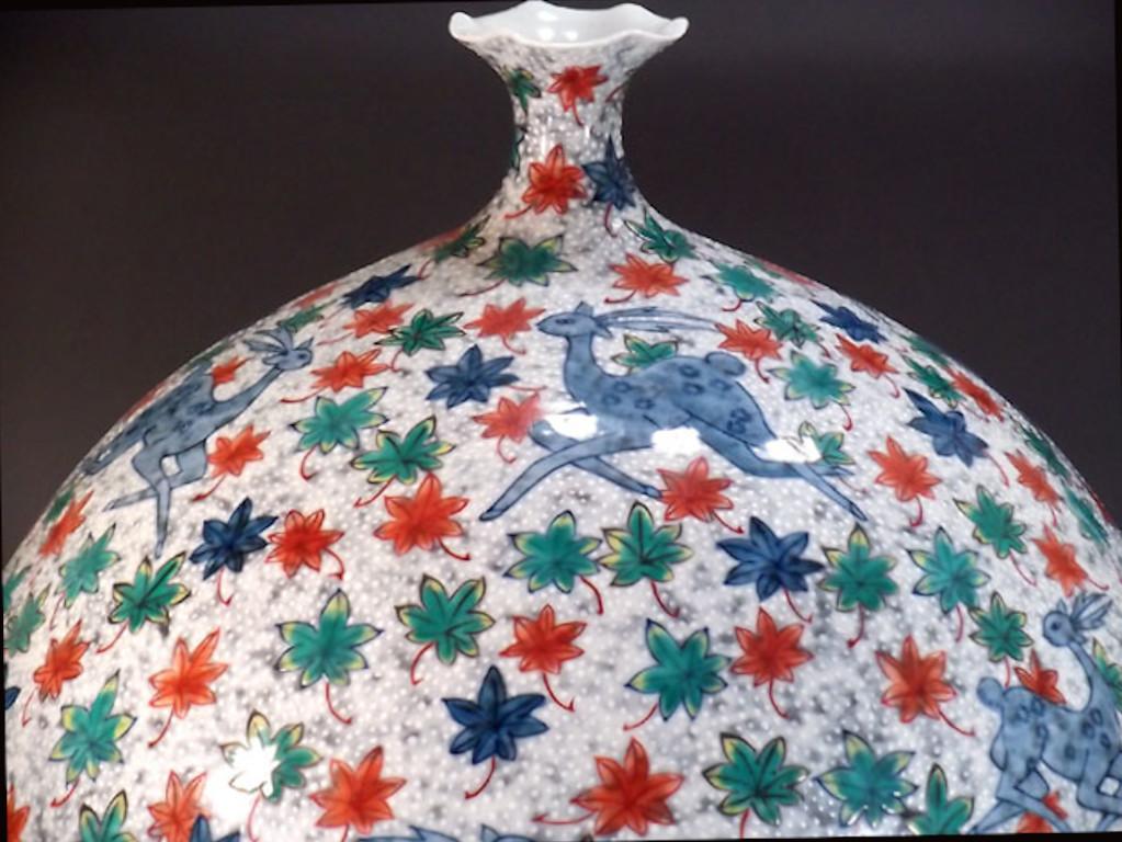 Exceptional contemporary Japanese decorative porcelain vase, intricately hand painted in various shades of blue, green and red set against an elegant ovoid body, a signed work by highly acclaimed award-winning master porcelain artist from the