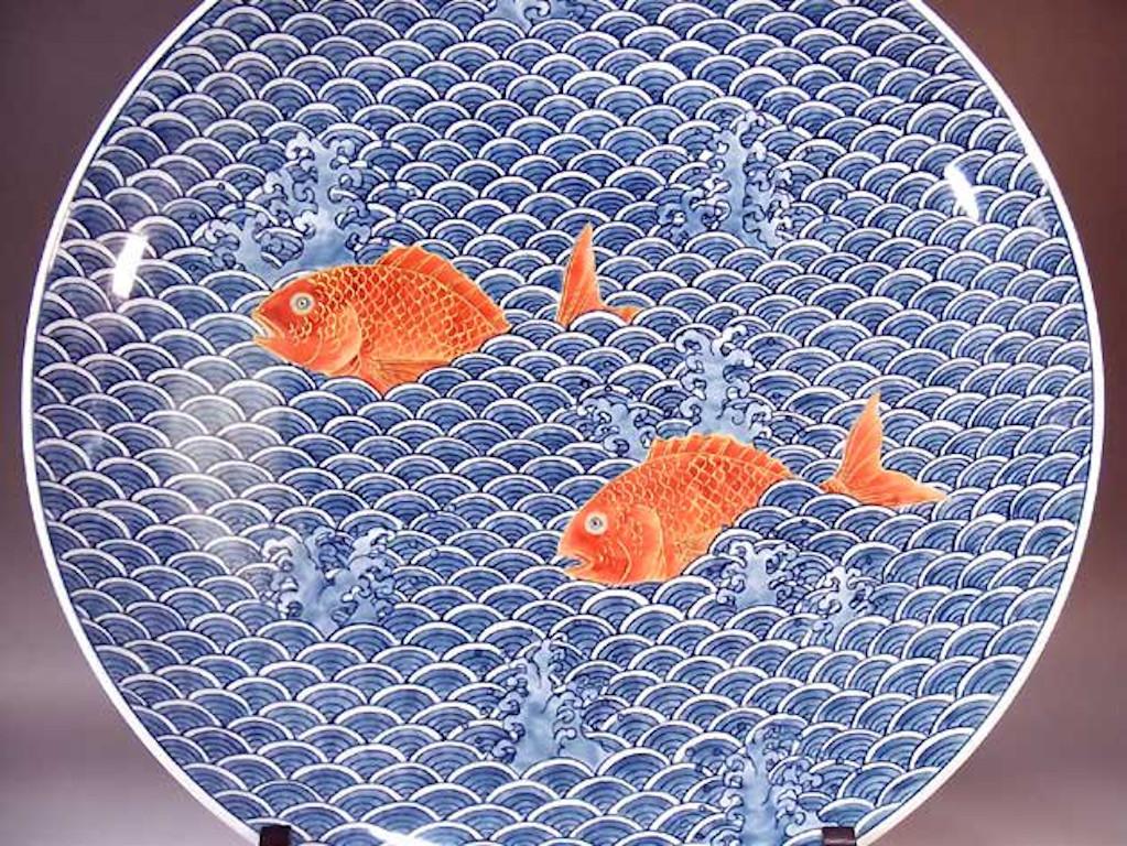 Exquis chargeur en porcelaine décorative japonaise contemporaine, peint à la main en rouge et bleu sous glaçure dans différentes nuances de bleu, une œuvre signée par un maître artiste porcelainier primé et largement admiré de la région