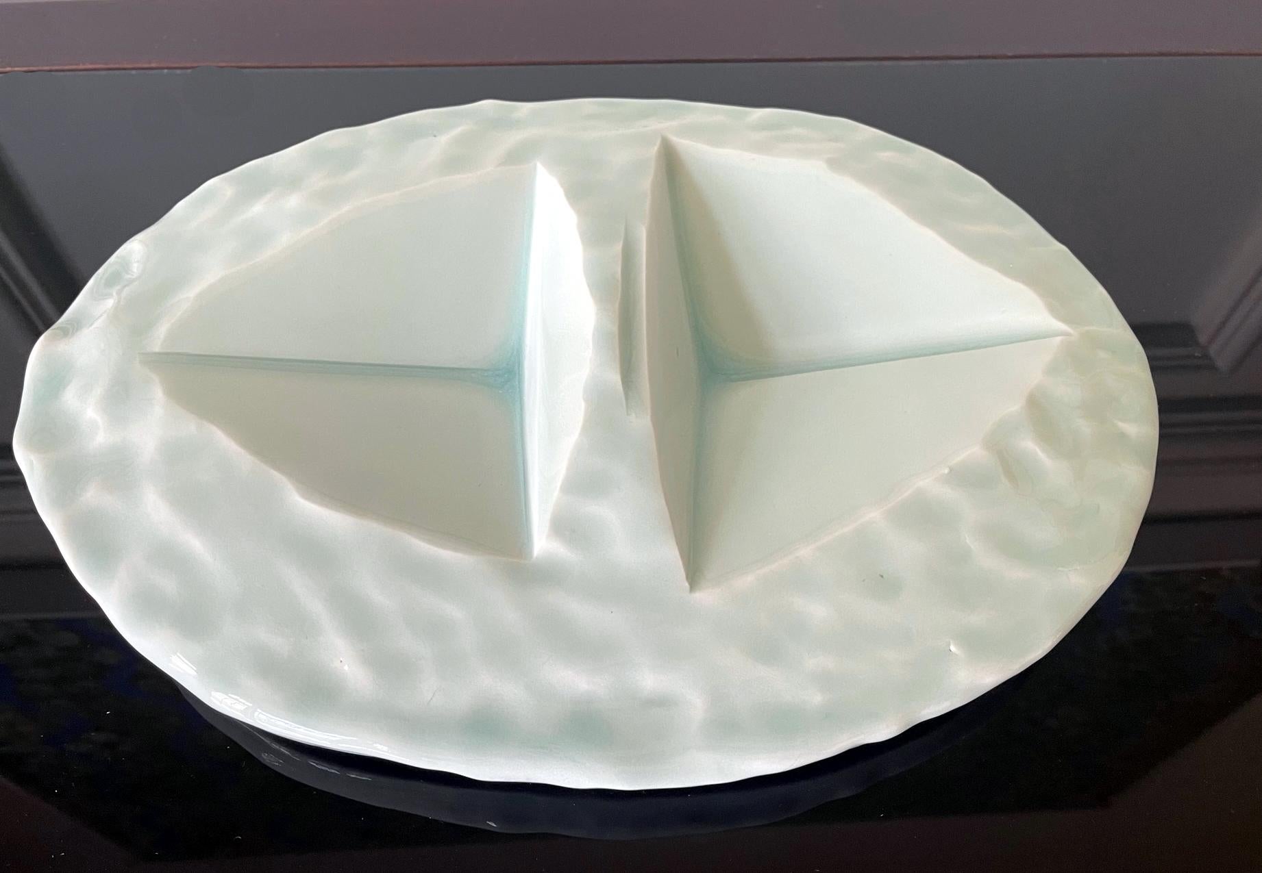 A richly glazed ceramic sculptural slab in the shape of a centerpiece plate by Japanese ceramic artist Yoshikawa Masamichi (1946-). The highly abstract piece was hand built with intentional irregularity and covered with a thick bluish-green