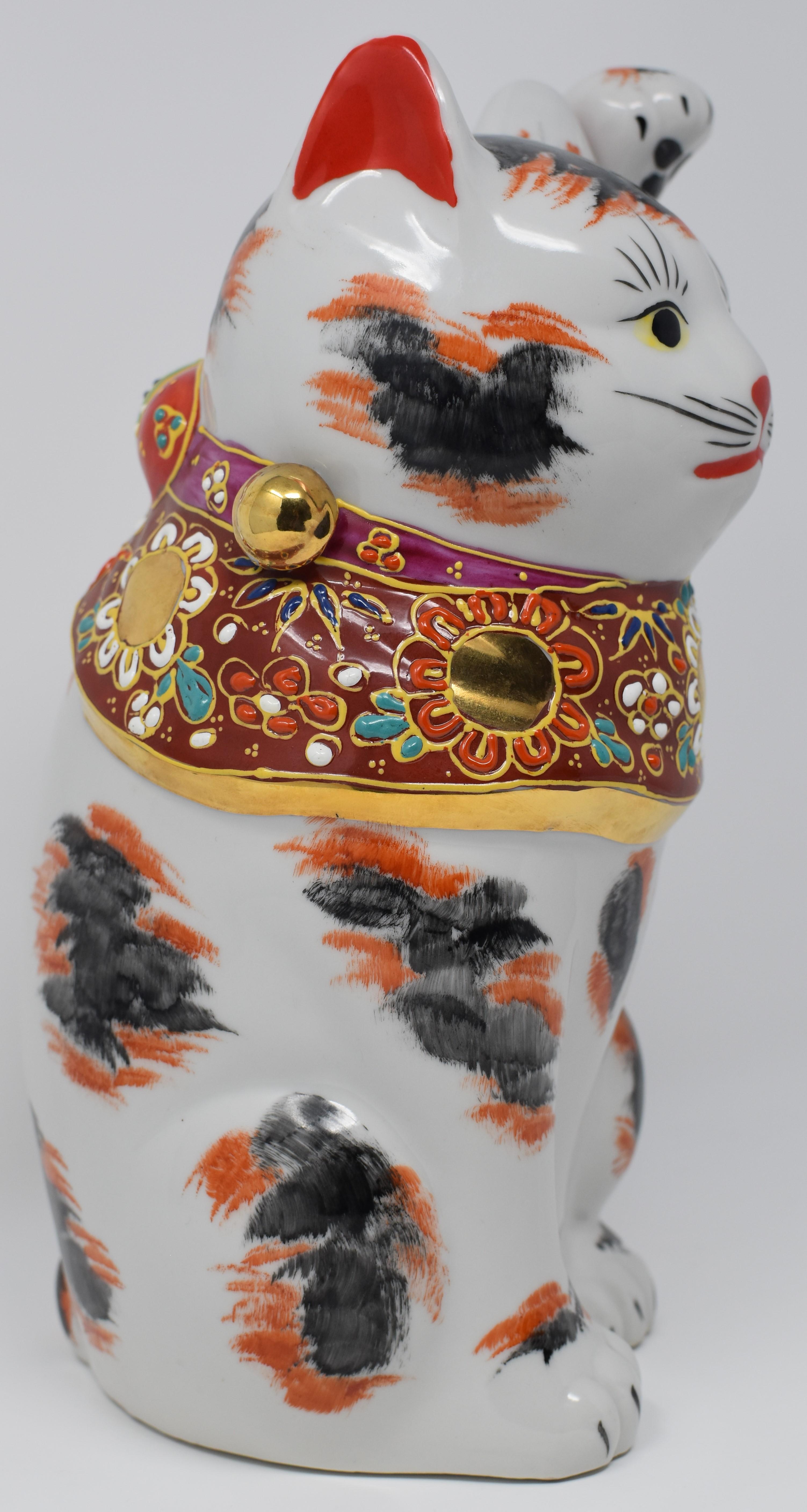 This charming left-handed beckoning cat is a gilded and hand-painted porcelain piece from the Kutani region of Japan.
The beckoning cat comes in two varieties. The more common right-handed beckoning cat (with right paw raised) is said to bring money