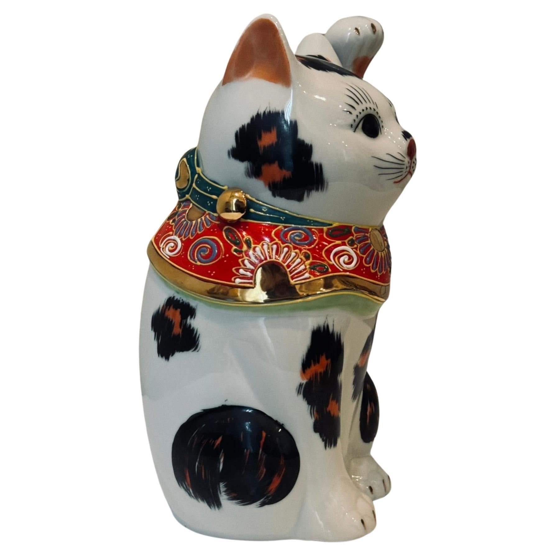 Charming beckoning cat with left paw raised is a gilded and hand painted porcelain piece from the Kutani region of Japan.
Beckoning cats come in two varieties. The more common right-handed beckoning cat (with right paw raised) is said to bring money
