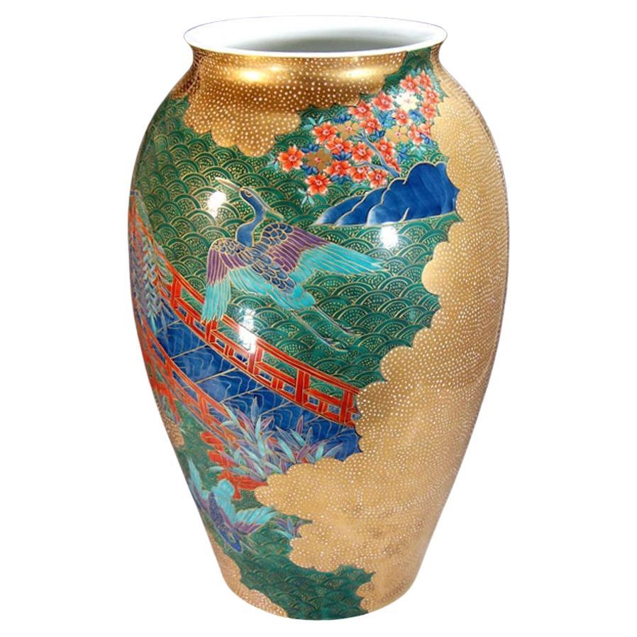 Extraordinary Japanese contemporary decorative porcelain vase, stunningly gilded and intricately hand-painted in blue, green and red on a elegantly shaped body, featuring a mesmerizing combination of polychrome overglaze and extensive gilding. It is