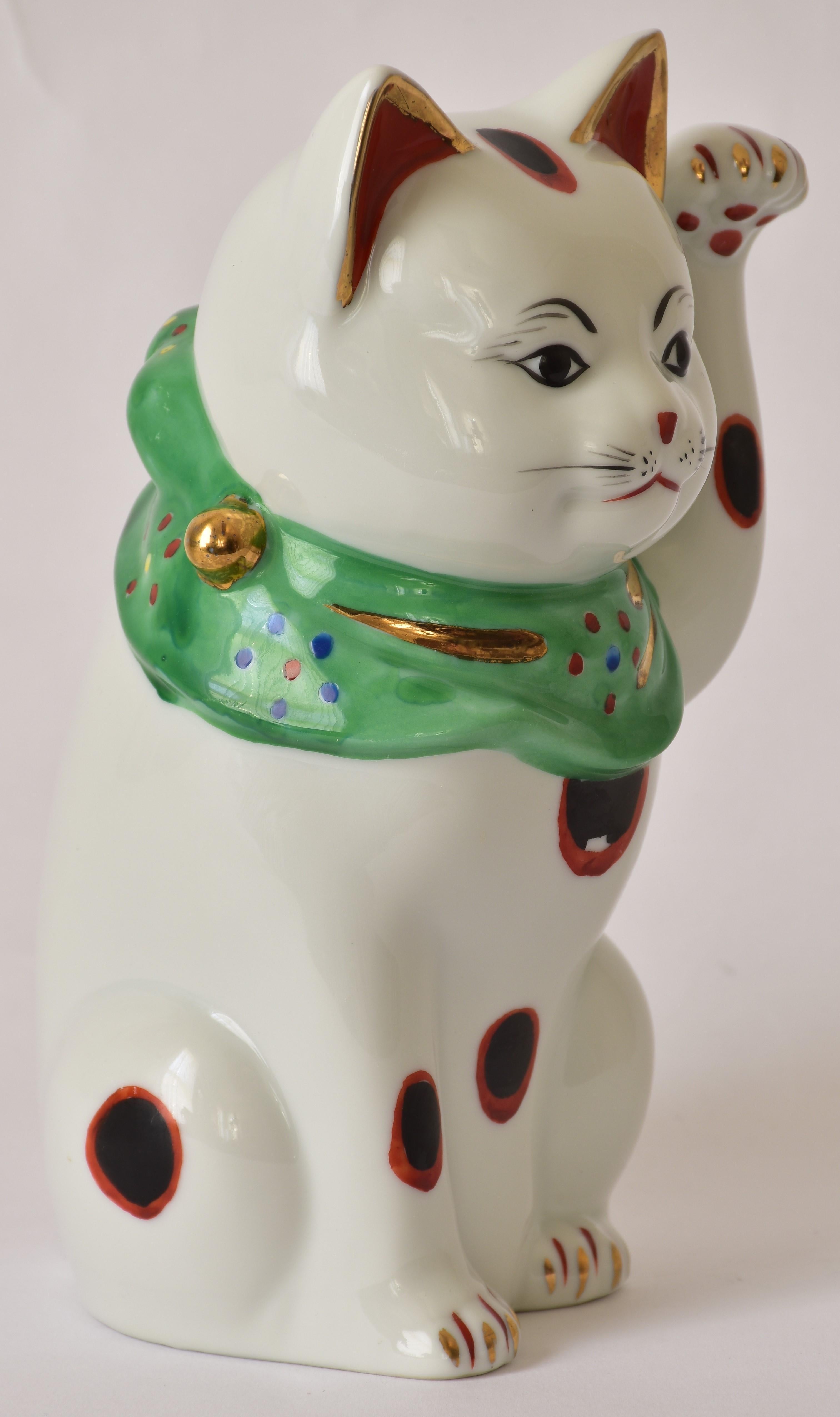Charming left-handed Japanese porcelain beckoning cat (maneki neko,) gilded and hand painted porcelain piece from the Kutani region of Japan. The beckoning cat comes in two varieties. The more common right-handed beckoning cat (with right paw