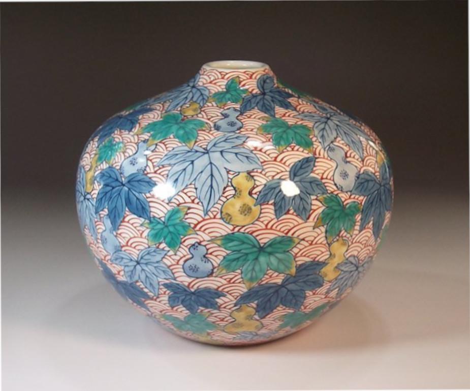 Mesmerizing Japanese contemporary porcelain decorative vase hand-painted on a beautifully shaped body, depicting plum blossom in red and medieval palaces in shades of blue and details in gold, a signed masterpiece by highly acclaimed Japanese master