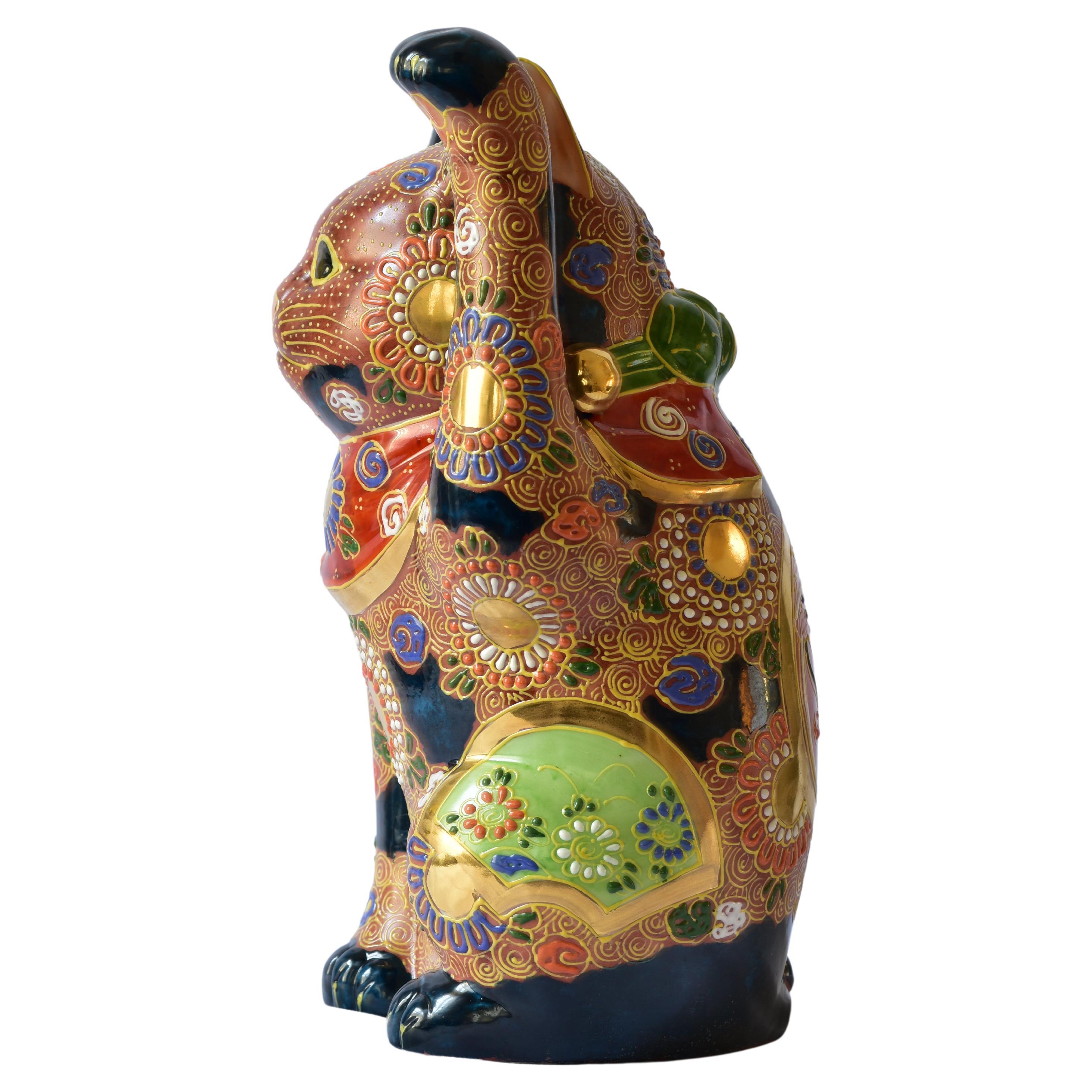 Exquisite Japanese Contemporary porcelain beckoning cat, a uniquely and intricately gilded and hand painted porcelain sculpture from the Kutani region of Japan. The cat raising his left paw is adorned with multiple golden medallions and is covered