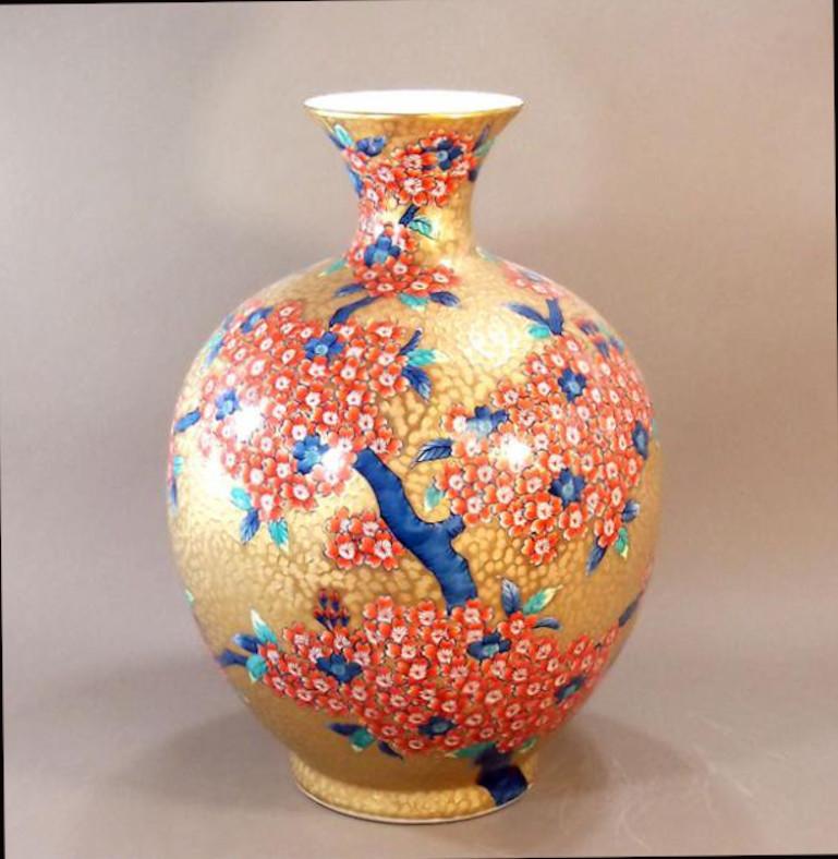 Exceptional Japanese contemporary large decorative porcelain vase in an absolutely stunning dimpled globular shape in gold with a long neck, adorned with hand painted clusters of cherry blossoms in iron red, set against a dimpled background in gold,