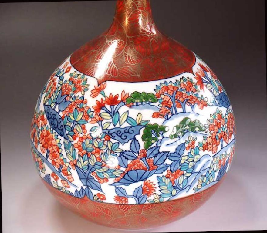 Contemporary gilded and intricately hand painted Japanese porcelain vase in an elegant bottle shape, hand painted in red with generous gold detailed, decorated with a wide band with a stunning floral motif in blue and red, a masterpiece by widely