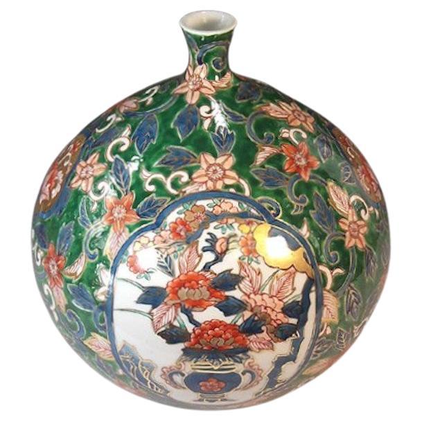 Exquis vase décoratif en porcelaine japonaise contemporaine, peint à la main en rouge et vert avec de généreux détails dorés sur un corps en forme de bouteille, représentant des panneaux en forme d'écailles de paysages séculaires du Japon entourés