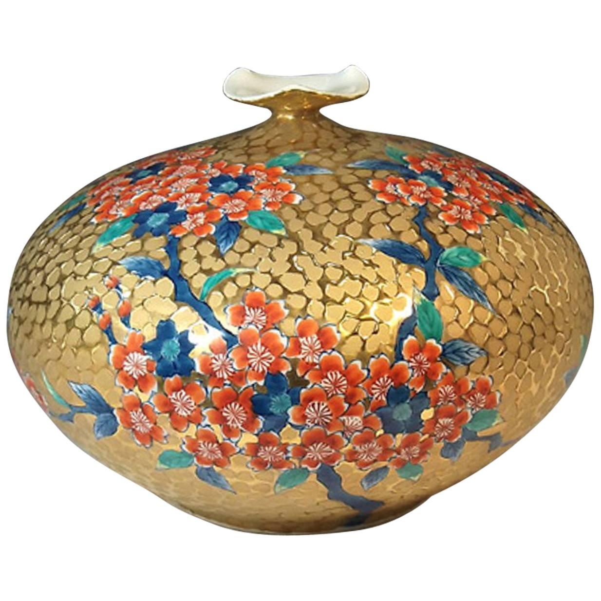Exquisite japanese contemporary gilded and dimpled porcelain vase, decorated with cherry blossoms in iron red on a beautifully shaped body in gold, a signed work by widely respected award-winning master porcelain artist in Imari-Arita style. This