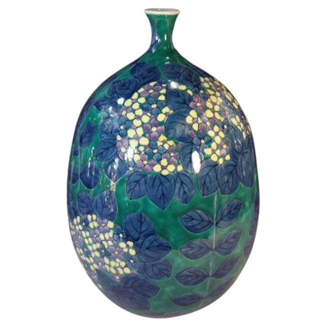 Exquisite contemporary Japanese decorative porcelain vase, hand painted in vivid blue, green, yellow and purple on a beautifully shaped body. This piece is by widely acclaimed master porcelain artist in traditional patterns of the Imari-Arita region