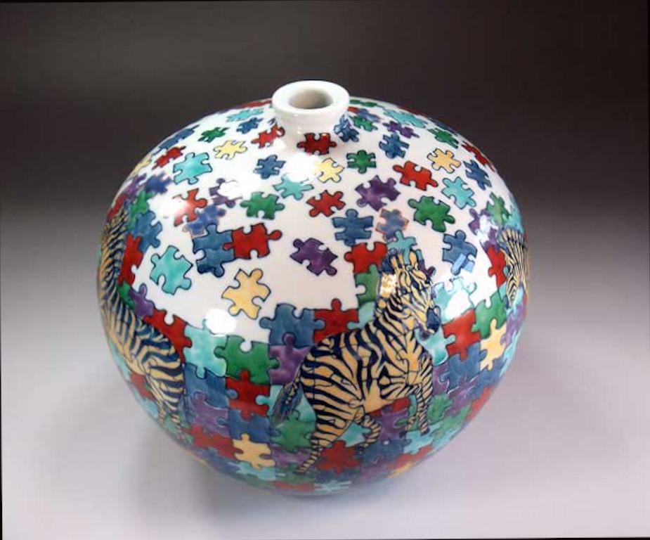 Contemporary Japanese decorative porcelain vase, hand painted in vivid red, yellow, green and black on an ovoid shaped body to create an entertaining surface. This piece is by widely acclaimed master porcelain artist in traditional patterns of the