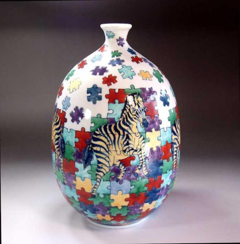Exquisite contemporary Japanese decorative porcelain vase, hand painted in vivid red, yellow, green and black on a beautifully shaped traditional body to create an entertaining surface. This piece is by widely acclaimed master porcelain artist in
