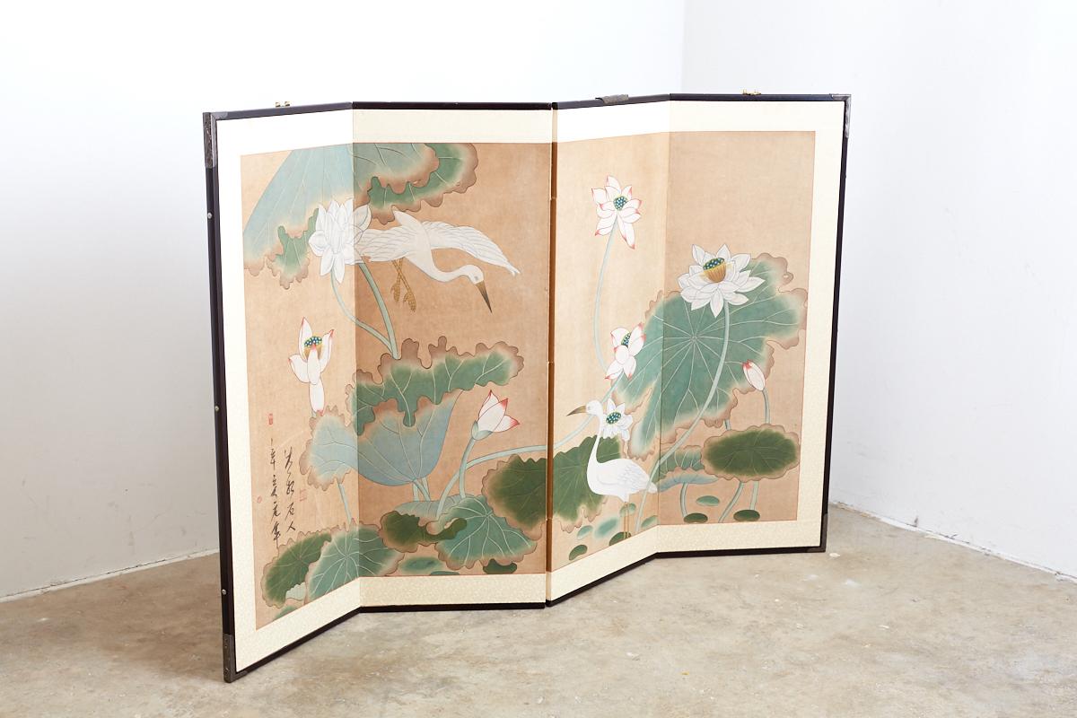 Beautiful painted Japanese byobu screen featuring white cranes among lotus blossoms. Painted on hand-made paper with hues of green and bold white colors. Bordered with a light silk brocade and set in an ebonized frame with shaped brass hangers.