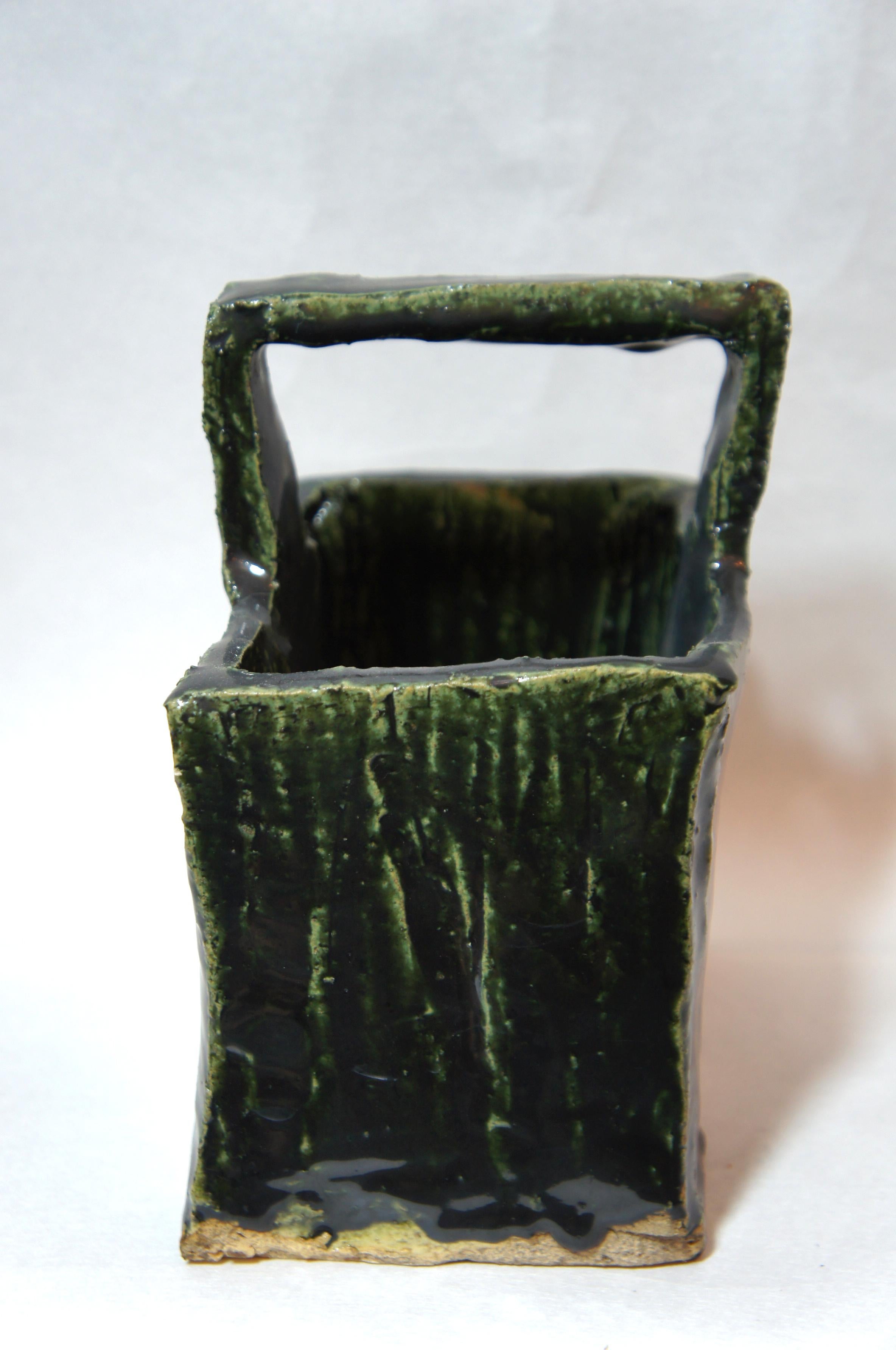 Beautiful dark green glazed Oribe ware vase with a handle.
In the bottom of vase, there is a small signe by Japanese artisan.

Oribe ware is a type of Mino Ware, which is traditionally made in Tajimi, Gifu Prefecture Japan. It was developed and