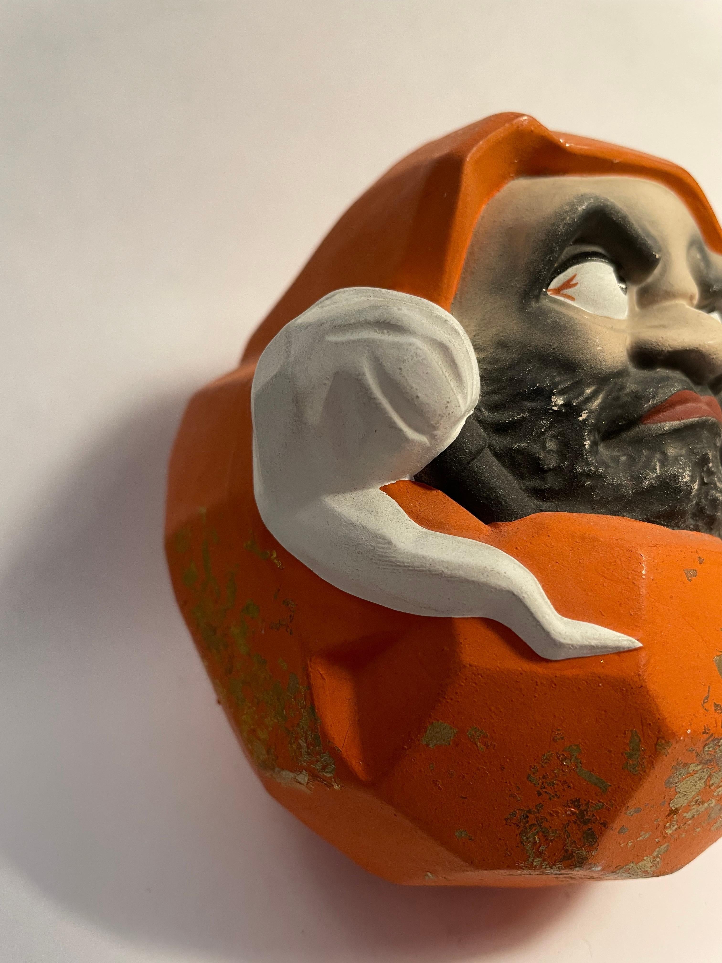 Il s'agit d'un objet en métal représentant Daruma qui a été fabriqué au Japon dans les années 2000, à l'époque Heisei. 

Un Daruma est une poupée creuse, ronde et traditionnelle japonaise, modelée d'après Bodhidharma, le fondateur de la tradition