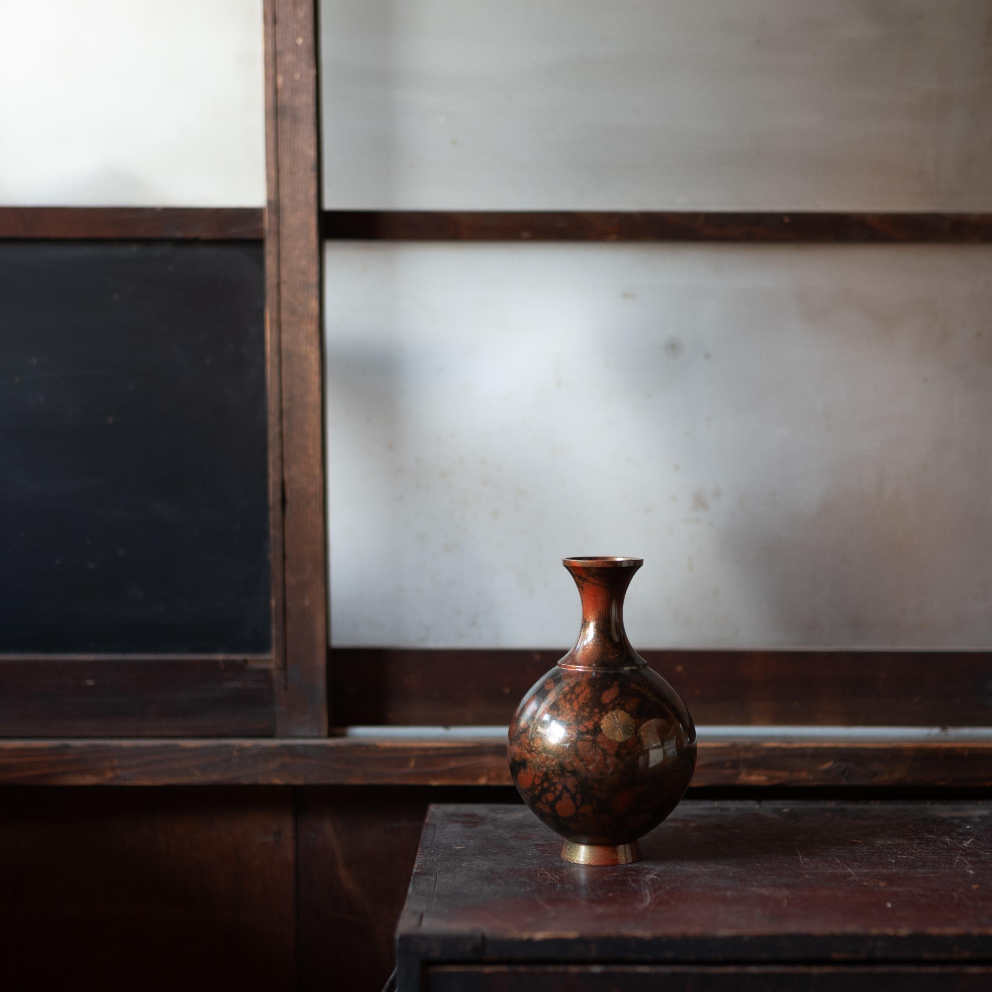 Vaso giapponese con corpo arrotondato e collo sottile, la forma ricorda sia le bottiglie di sakè che i vasi di fiori, incarnando l'estetica versatile delle arti decorative giapponesi. La superficie è rifinita con una profonda patina