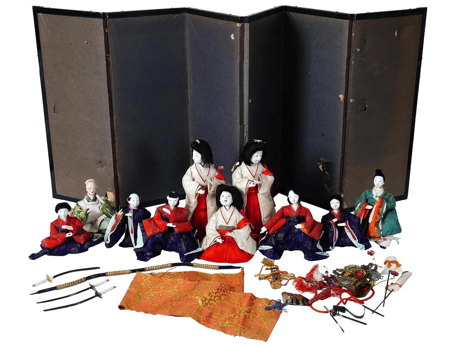 Una serie di bambole in argilla giapponese Sato Hakata Urasaki della metà del XX secolo, tessuti a mano, paraventi e altri pezzi. Le bambole sono adornate con costumi tradizionali realizzati e dipinti a mano. Il set comprende le statuette della