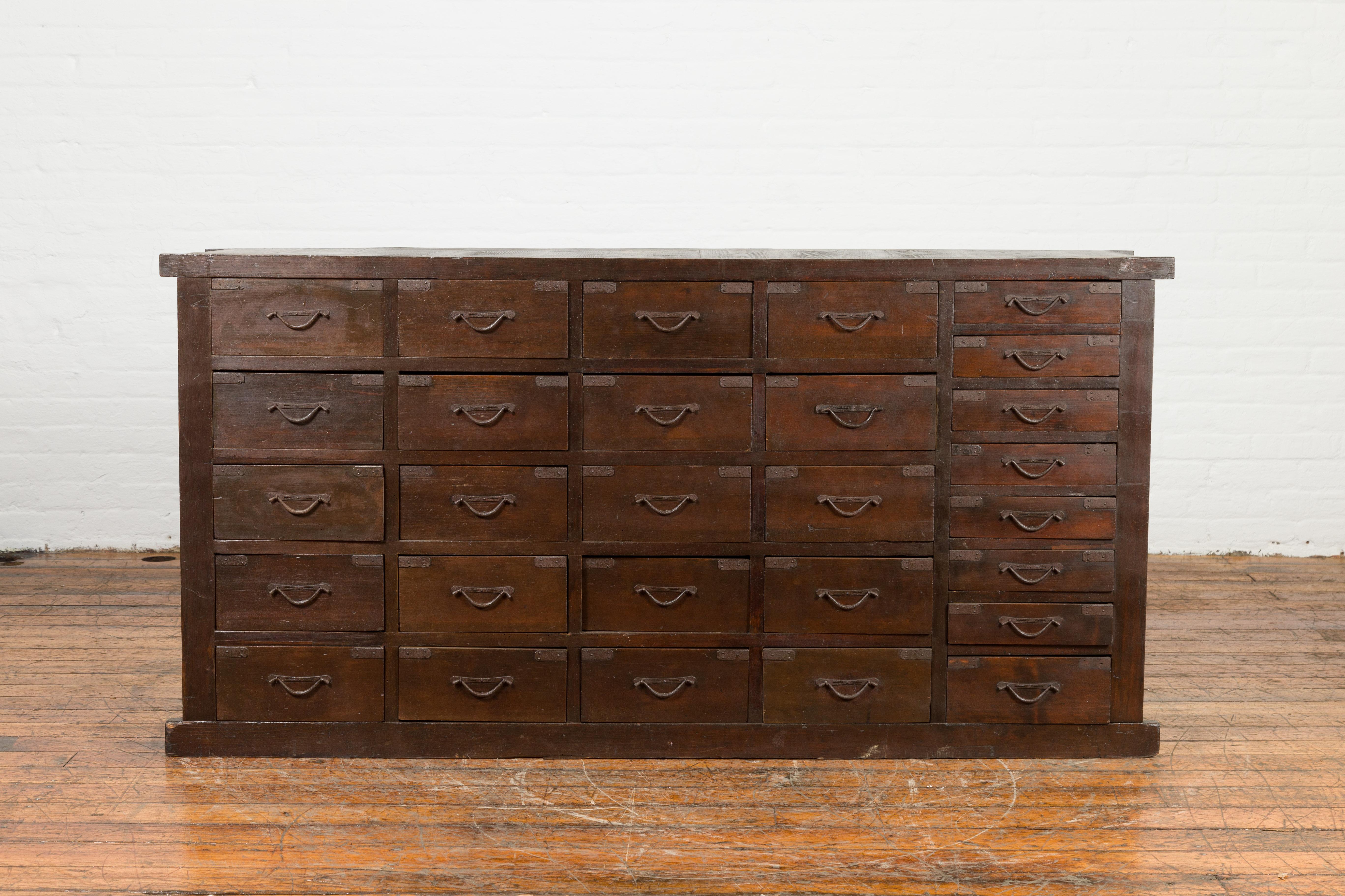A large Japanese antique apothecary chest from the early 20th century, with 28 drawers and brown patina. Created in Japan during the early years of the 20th century, this apothecary chest features a rectangular top sitting above a perfectly