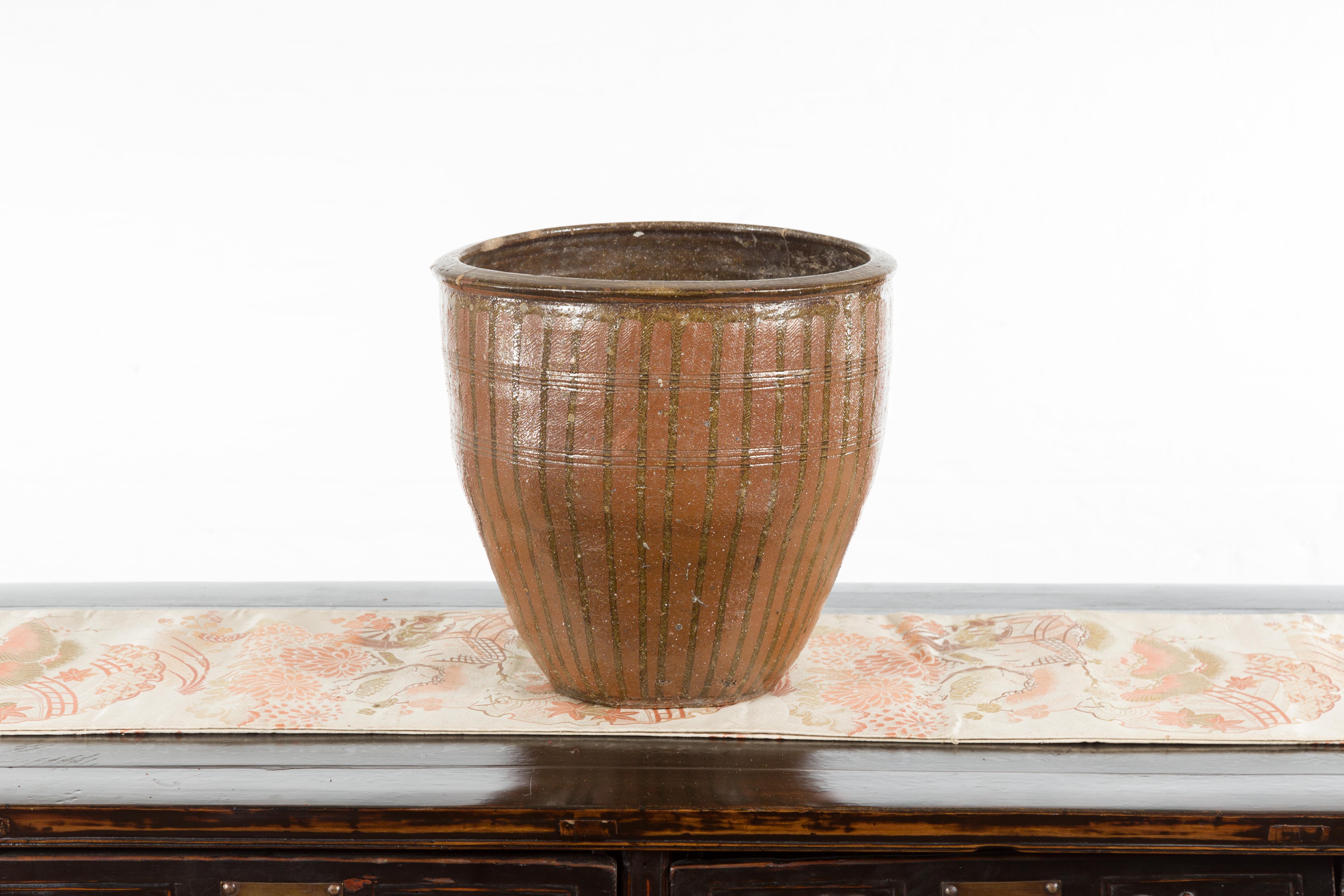 A Japanese antique Tamba Tachikui Ware pot from the early 20th century with dripping. Boasting a lovely brown color accented with dripping and horizontal incised accents, this Japanese pot was produced in one of Japan’s six famous ancient kilns.