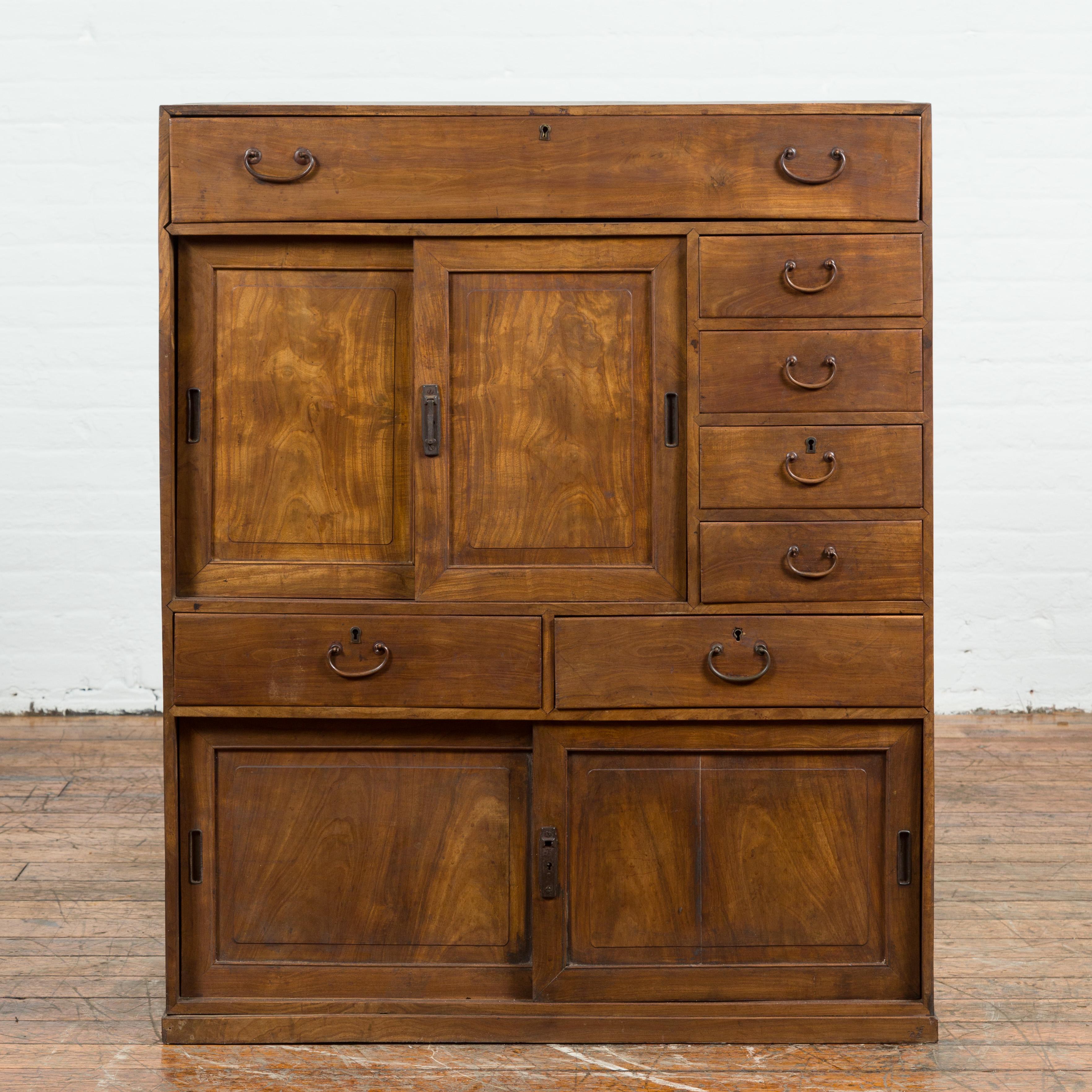 A Japanese Taisho period small cabinet from the early 20th century with sliding doors and seven drawers. Created in Japan during the early years of the 20th century, this small cabinet features seven drawers and two pairs of sliding doors offering