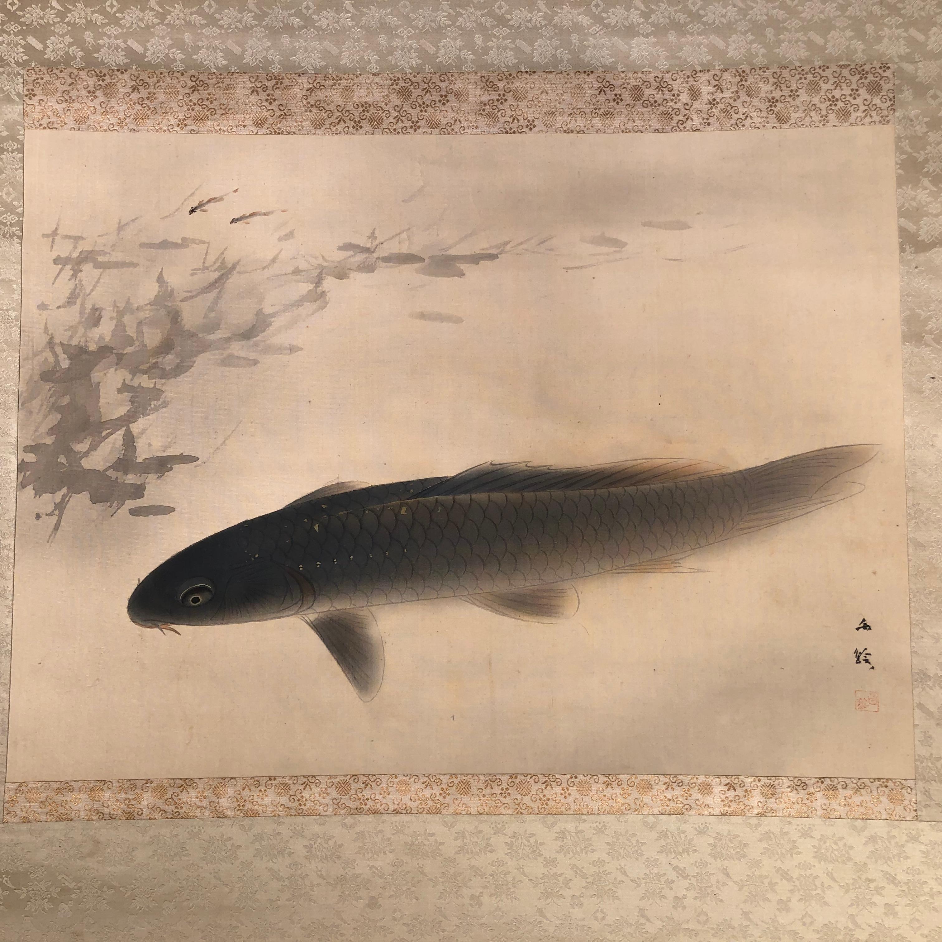 Japan, a magnificent Koi or Carp ripples the waters while safely guarding its tiny off spring in this auspicious art composition and hand painted early signed silk scroll dating to the Meiji era late 18th century. Koi soothe the mind and spirits and