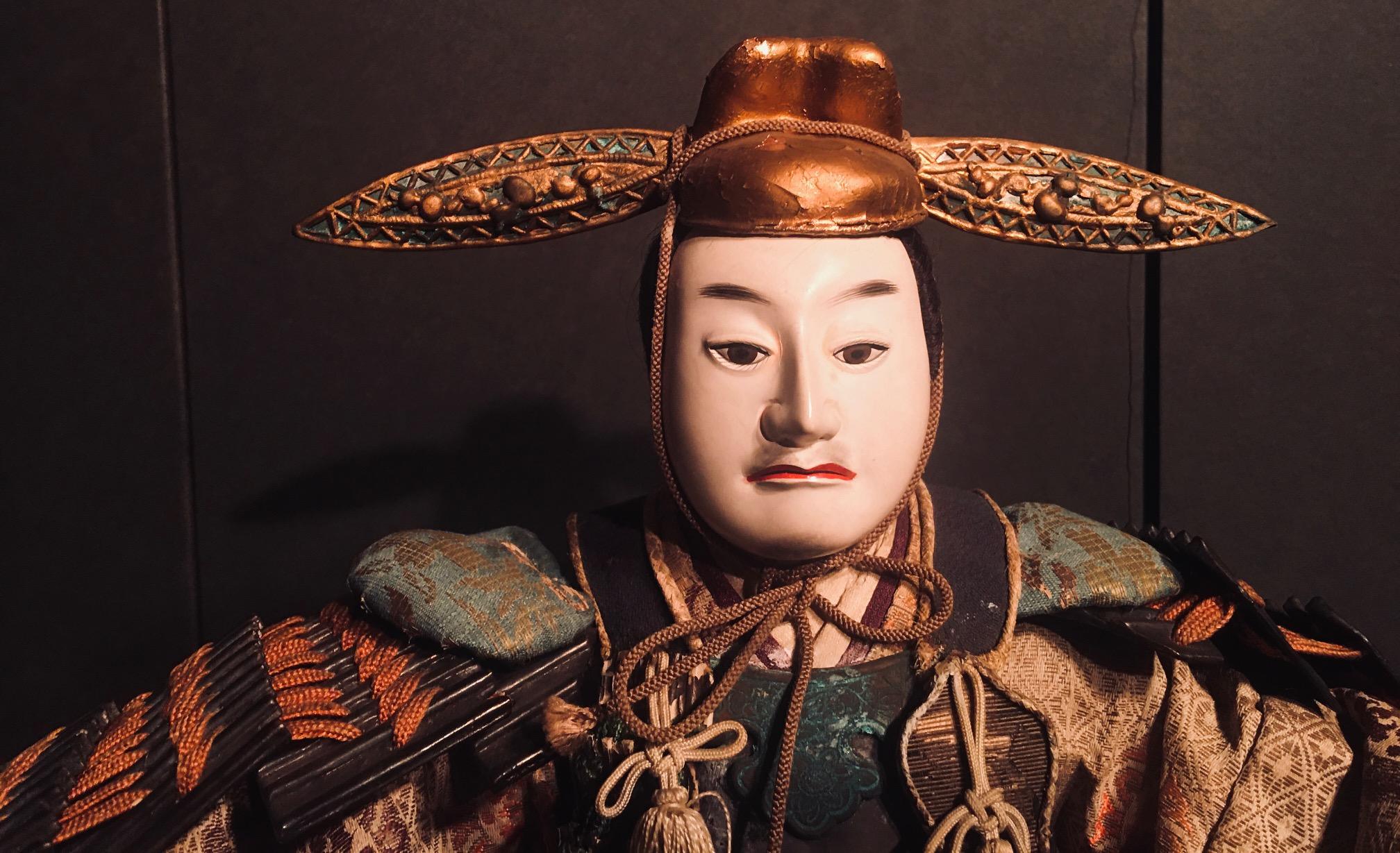 Japanese Edo Musha Ningyô (Boys Day Doll) depicting the legendary Toyotomi Hideyoshi, seated in court position and wearing elaborate brocade garments and gold lacquered armor. He is holding a gembun fan in his right hand and is wearing a Classic