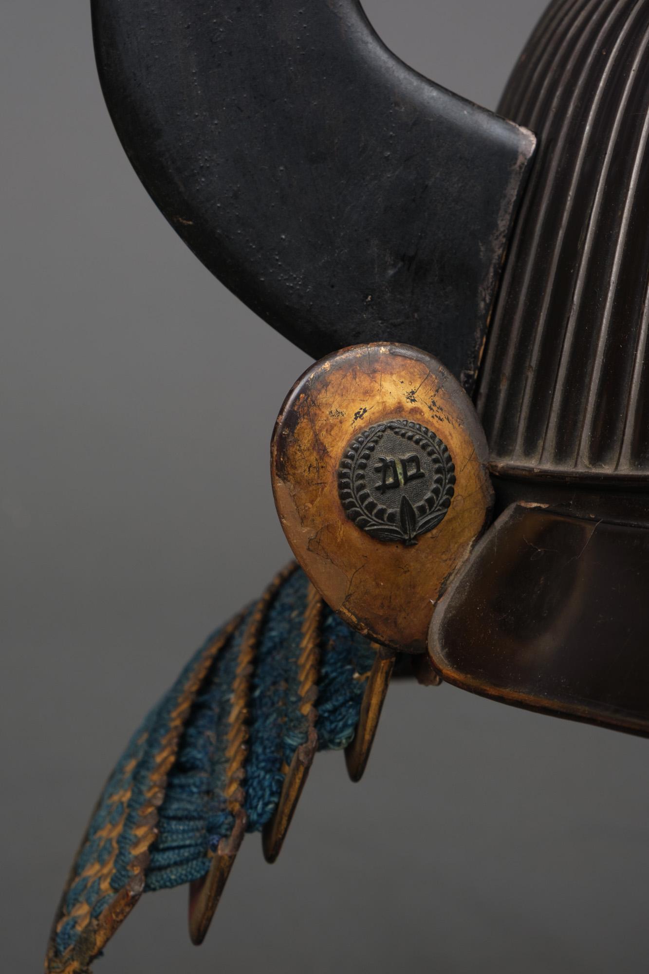 An old and exceptional completely lacquered akoda-nari suji’bachi kabuto (helmet with raised ridges) with a bronze maedate (decorative front piece) shaped like a spade, and mounted by impressively large black lacquer wakidate (side decoration) in