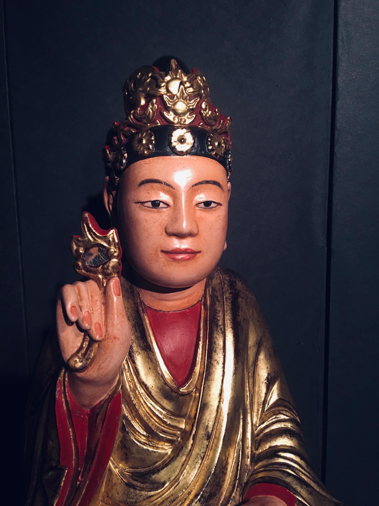 Vietnamese 19th century carved, lacquered and gilt Bodhisattva holding a secret flower. The Bodhisattva is seated on a lotus, which represents the symbol of fortune. This symbol can be found throughout Buddhism. It features a mystical presence.