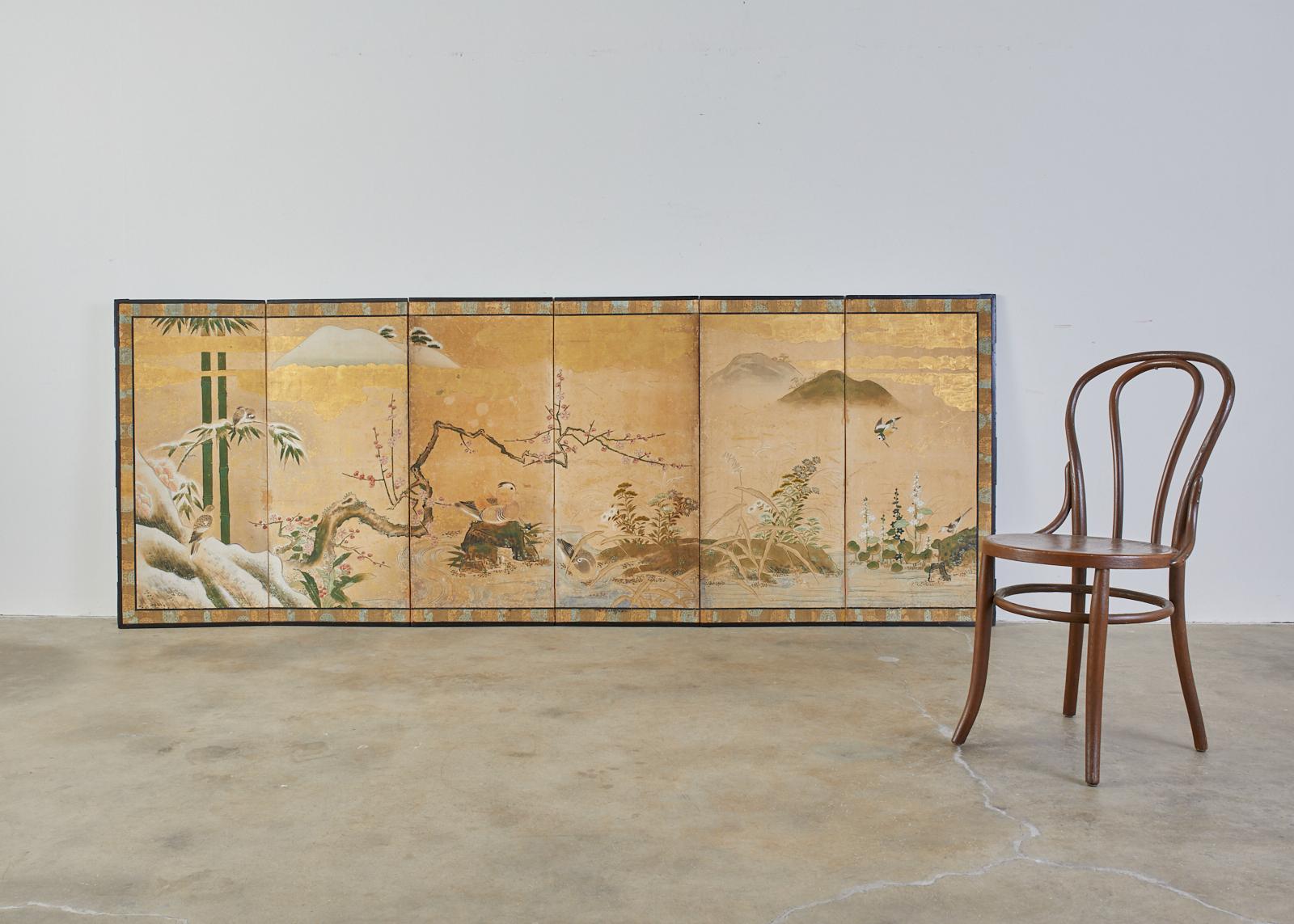Early 18th century Japanese Edo period six-panel screen depicting a seasonal winter landscape. The idyllic scene features ducks and birds with flowers of fall and winter by water’s edge. Beautifully crafted with ink and natural color pigments on
