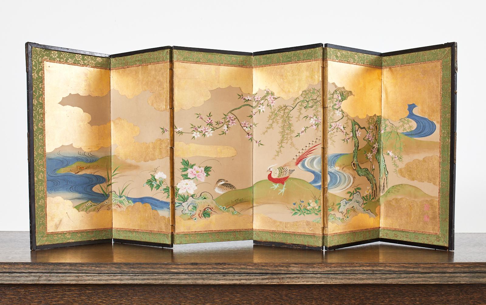 Fantastic diminutive Japanese Edo period table top screen depicting a lively water landscape with flora and fauna. The screen is beautifully painted on gold leaf with a pair of pheasants and flowering Sakura or cherry along a deep blue river. Late