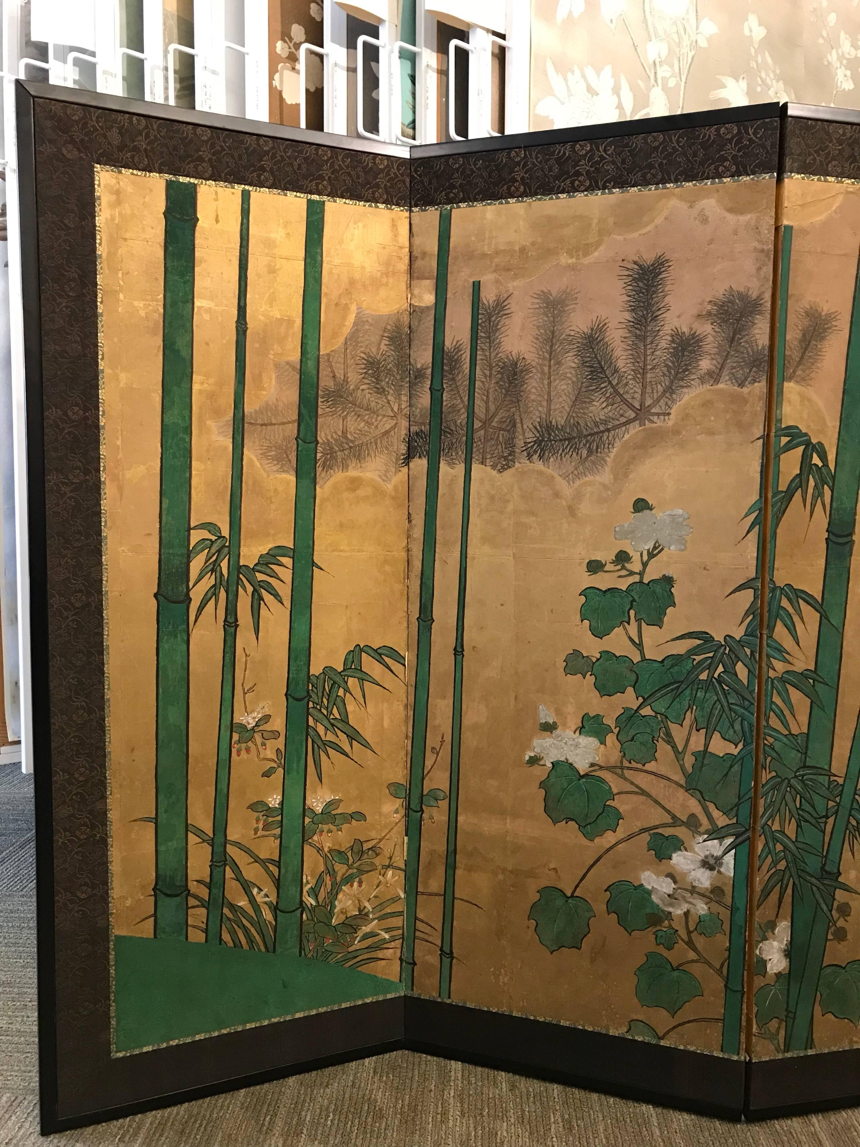 A 19th century eight panel Japanese screen with bamboo, pines, and gold leaf clouds.