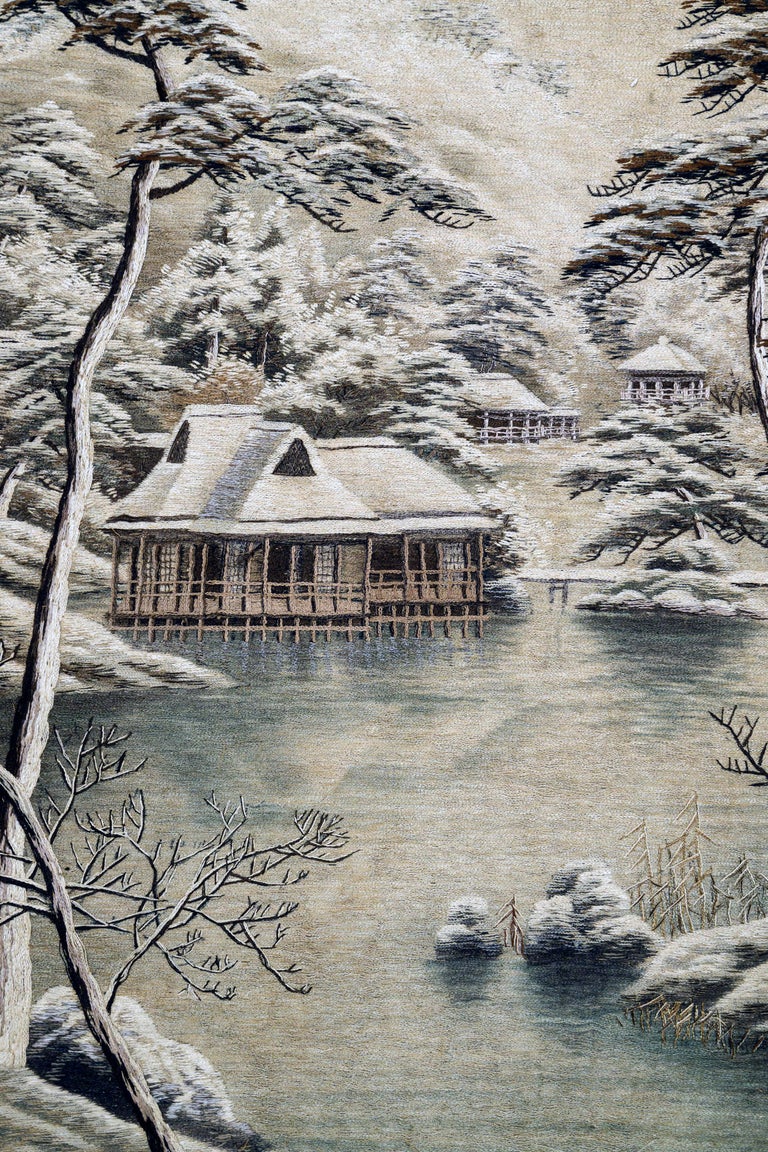 A Japanese silk embroidery landscape scenery panel depicting a temple compound set in a wintery forest among snow-covered towering pines. The compound is centered around a group of pavilions stilted on the edge of a pond. More buildings were seen in