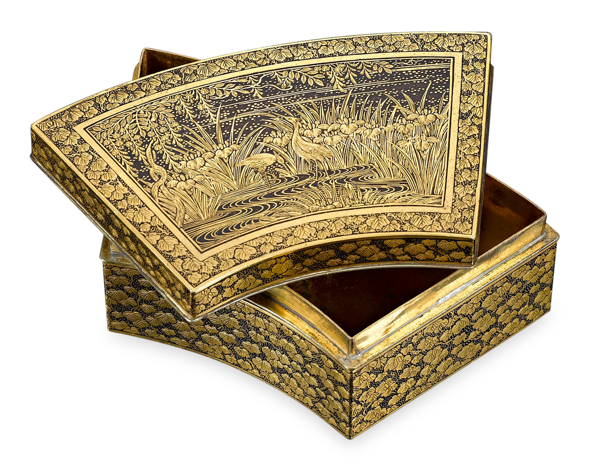 This rare and beautiful Japanese box exhibits a superb level of enamel artistry and craftsmanship. Formed in an elegant fan shape, this exquisite container is adorned with intricate engraving on every surface, highlighted by contrasting enamel