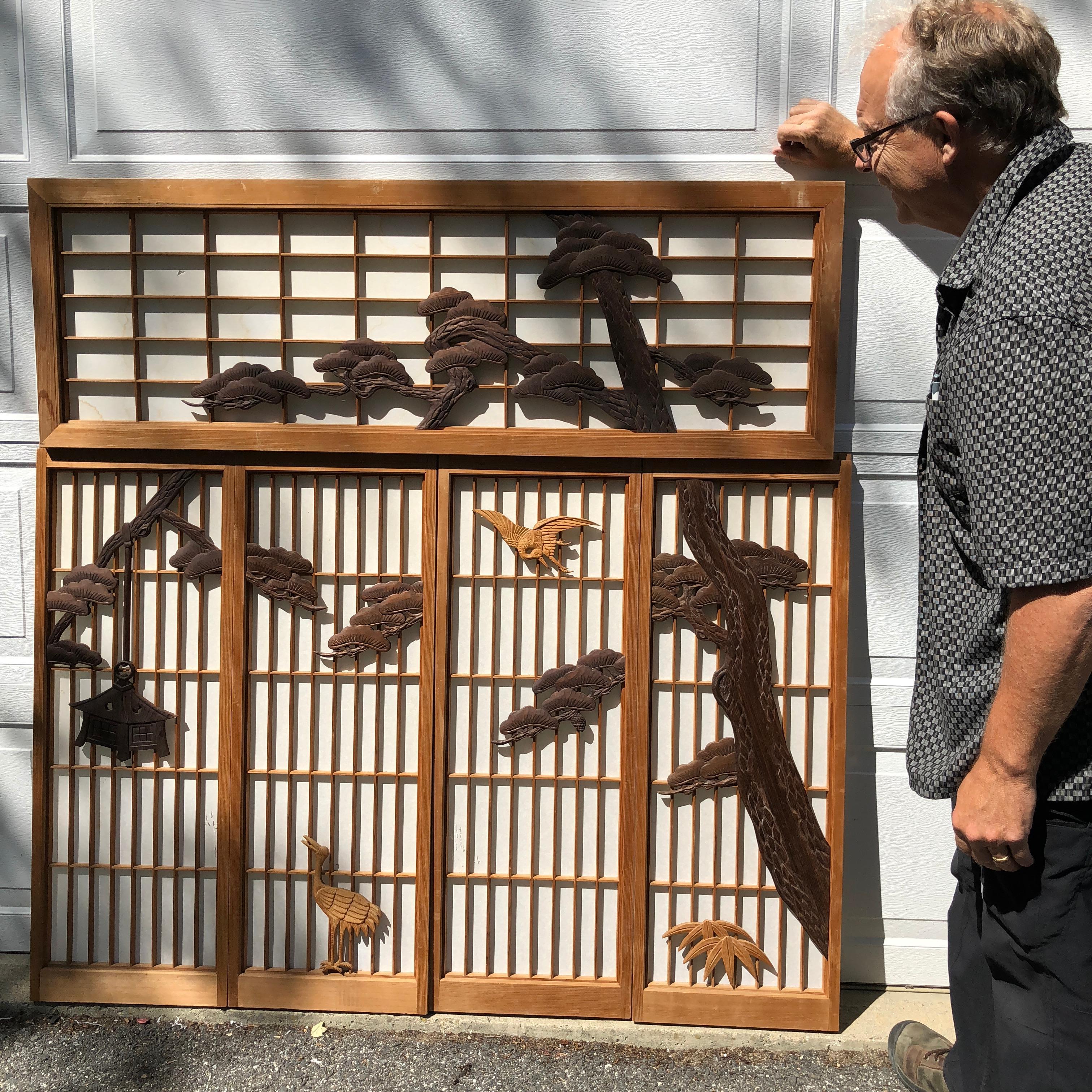 Japan, a fine hand-carved wooden Shoji screen set of five (5) panels featuring a stunning black pine tree, birds, and lantern, all hand-carved wooden designs. A shoji is a wall decoration, door, window or room divider consisting of translucent paper