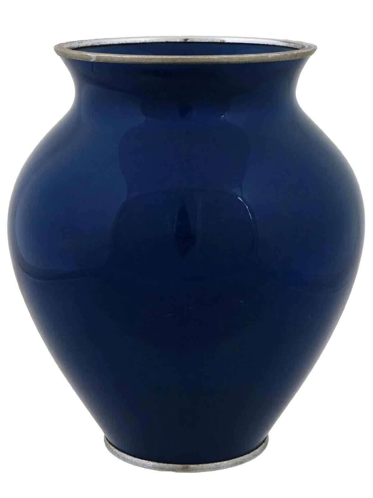 Jarrón japonés de esmalte sobre metal. El jarrón tiene un cuerpo de forma globular y un cuello ancho con boca estriada. El exterior de la vajilla está esmaltado con un diseño polícromo que representa flores de sakura y mariposas sobre un fondo azul