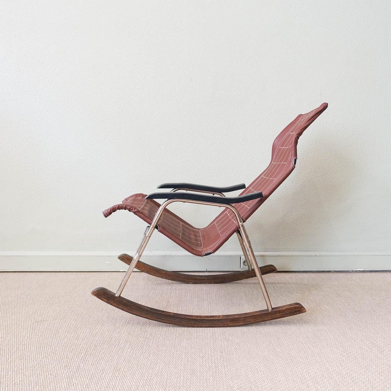 This folding modern rocking chair was designed by Takeshi Nii during the 1950s, in Japan. It has a brown leather upholstered, aluminum frame on wooden sleds and black bakelite armrests. This folding model is easy to storage and transport. 
It is a