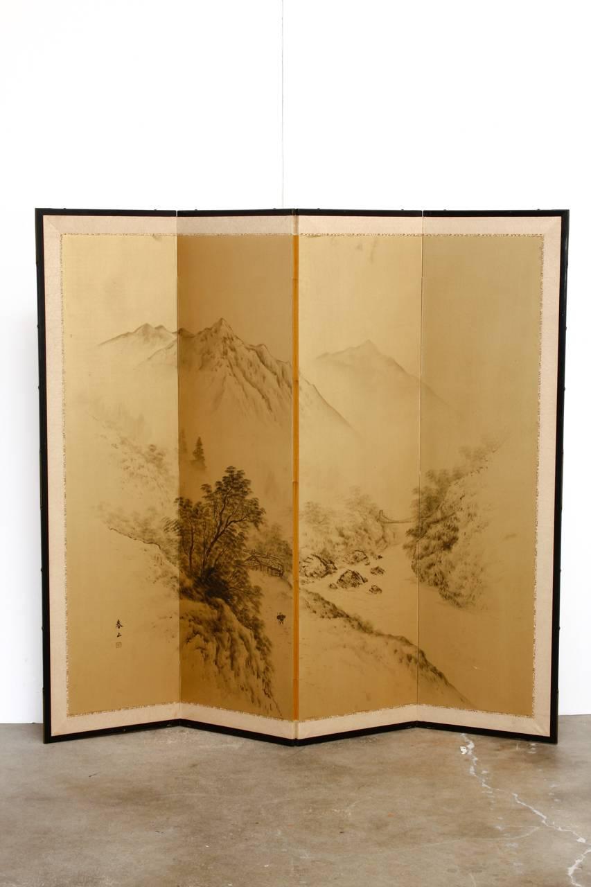 Large Japanese four-panel Byobu screen featuring a painted mountain landscape on a gilt background. Beautiful and delicate scene of rivers and valleys. Signed with a seal on the lower left corner and set in an ebonized wood frame with a silk brocade