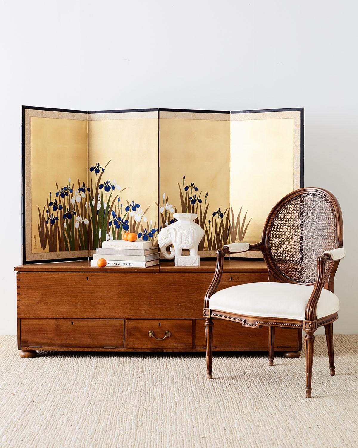 Colorful Japanese four-panel byobu screen of painted irises over shiny gilt squares. Vivid blue, green and yellow with white flowers decorate the screen. Signed and seal on left side. Set in an ebonized frame with a silk brocade border.