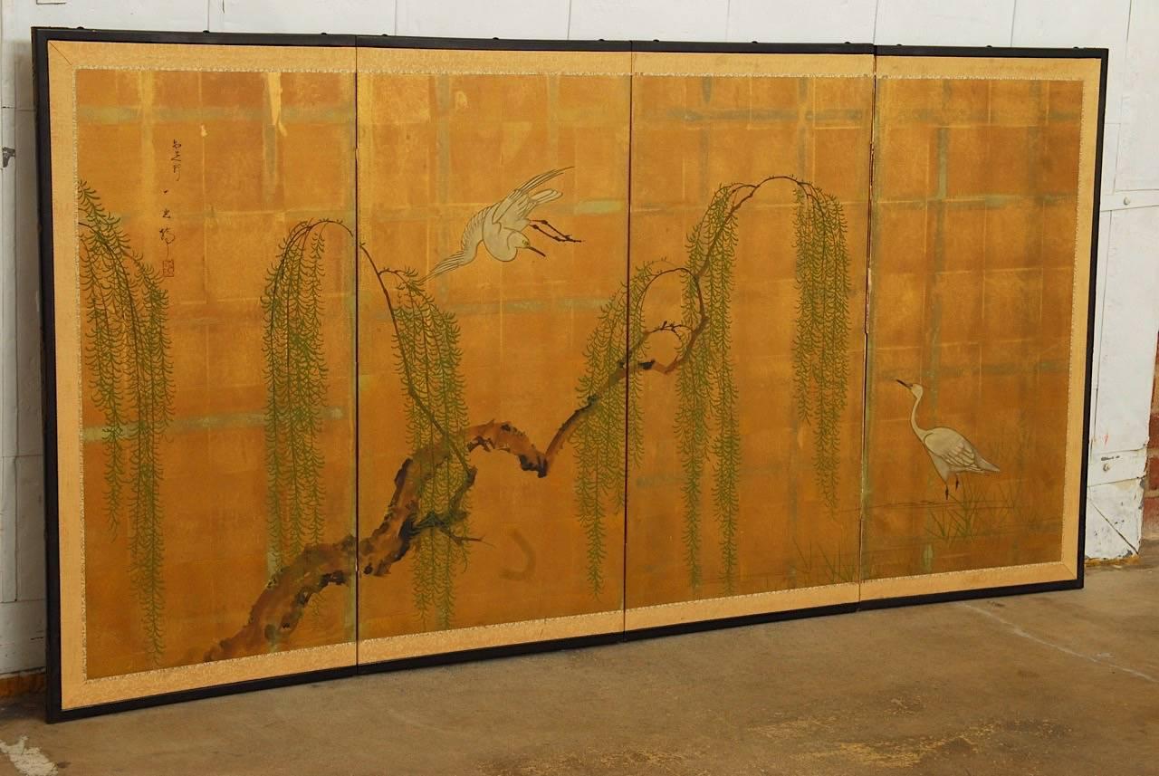 Early 20th century Japanese Meiji four-panel screen featuring cranes and a willow tree. Painted on squares of gold leaf with a rich patina and set in an ebonized wood frame with a brocade silk border. Signed and stamped upper left. Losses on back.