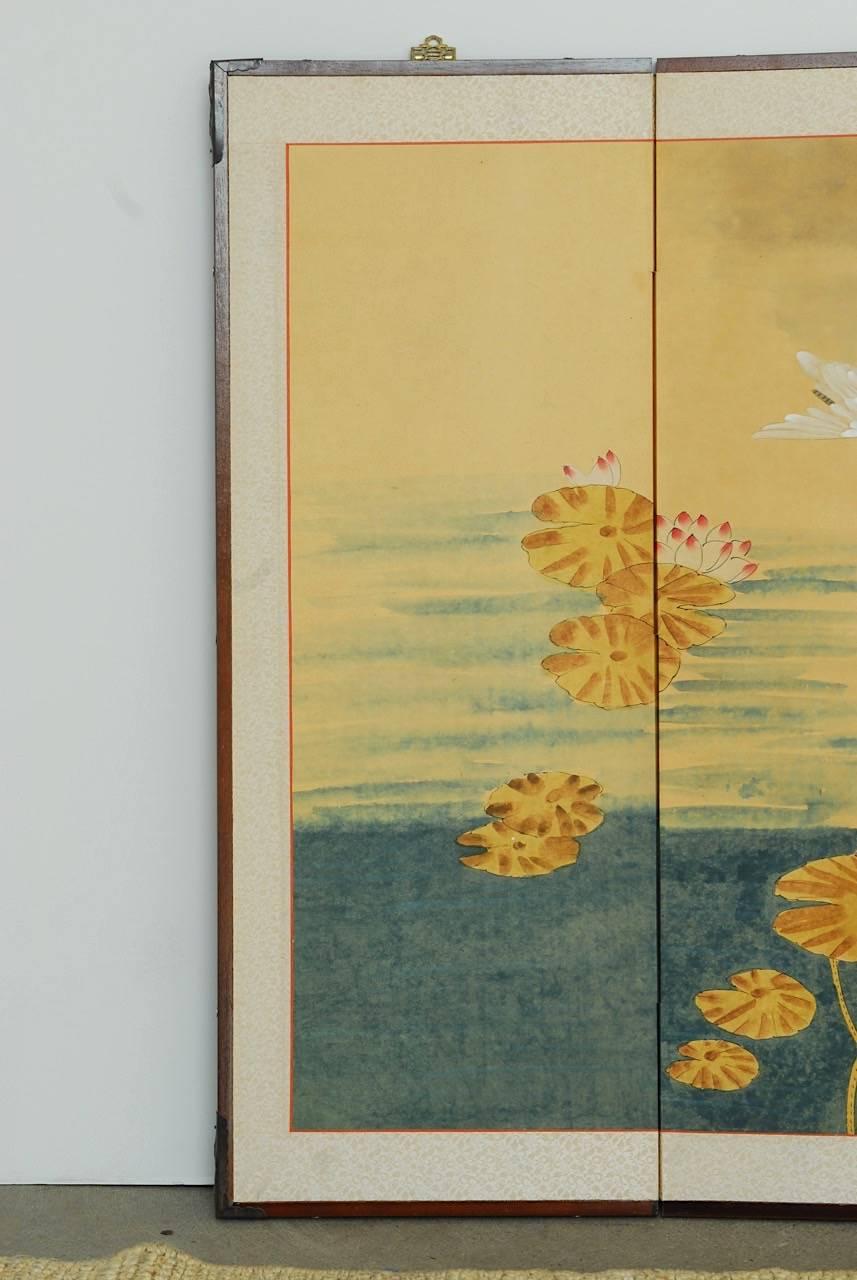 Idyllic Japanese four-panel Byobu screen depicting a hand-painted seascape of white egrets, wooden boat, and lily pads under a faint crescent moon. Vibrant colors of blue, white, pink, and brown stand out against the beige background. Signed with