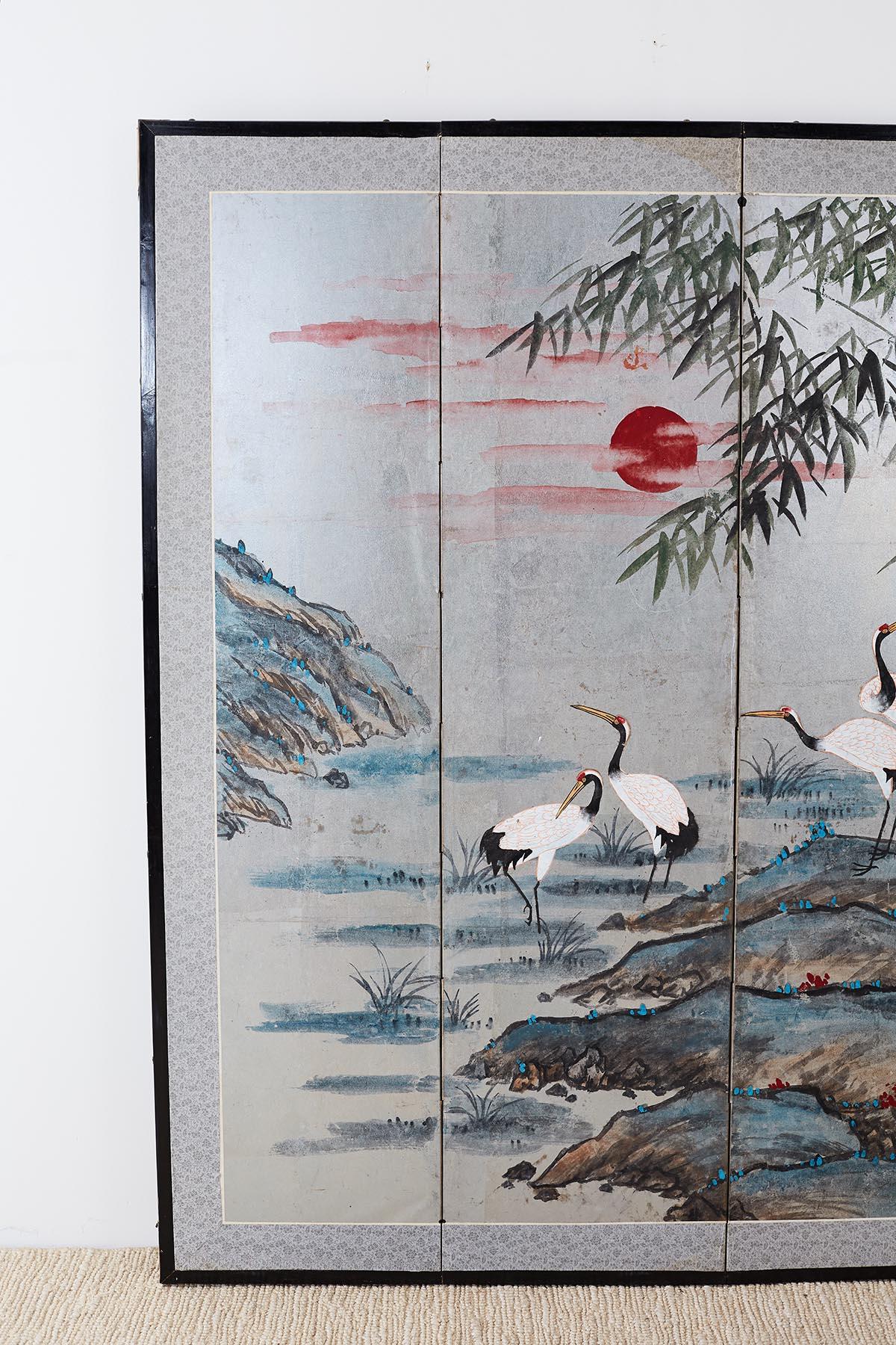 Colorful Japanese four-panel screen made in the kano school style depicting five Manchurian cranes or red-crowned cranes. Interesting landscape with a setting red sun and vivid blue colors. Four panel screen probably cut down from a six panel screen