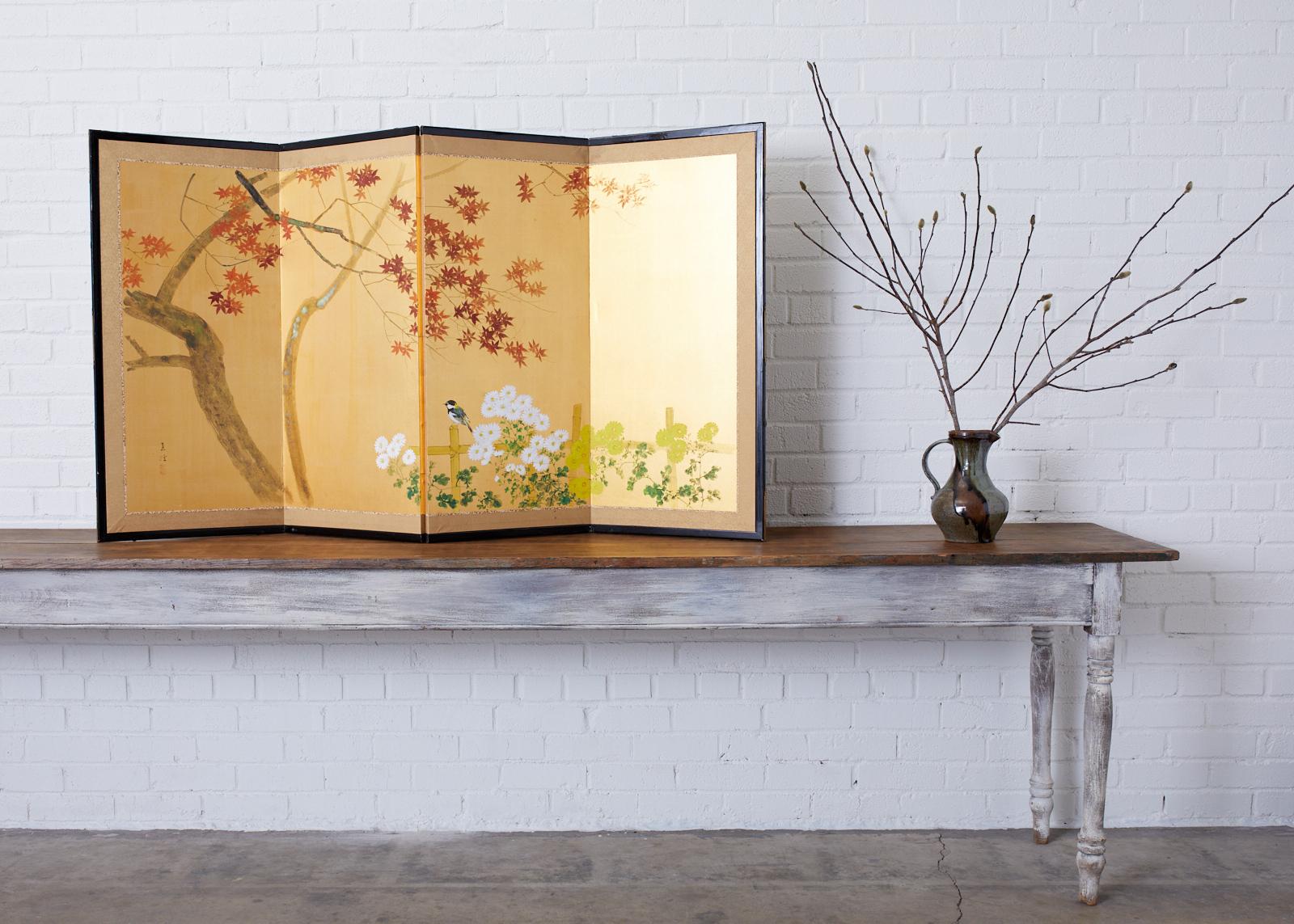Delightful Japanese Showa period four-panel screen depicting an autumn maple tree over a bamboo fence with flowering chrysanthemums and a small bird. Ink and color pigments painted on radiant gilt colored silk. Made in the Nihonga school style